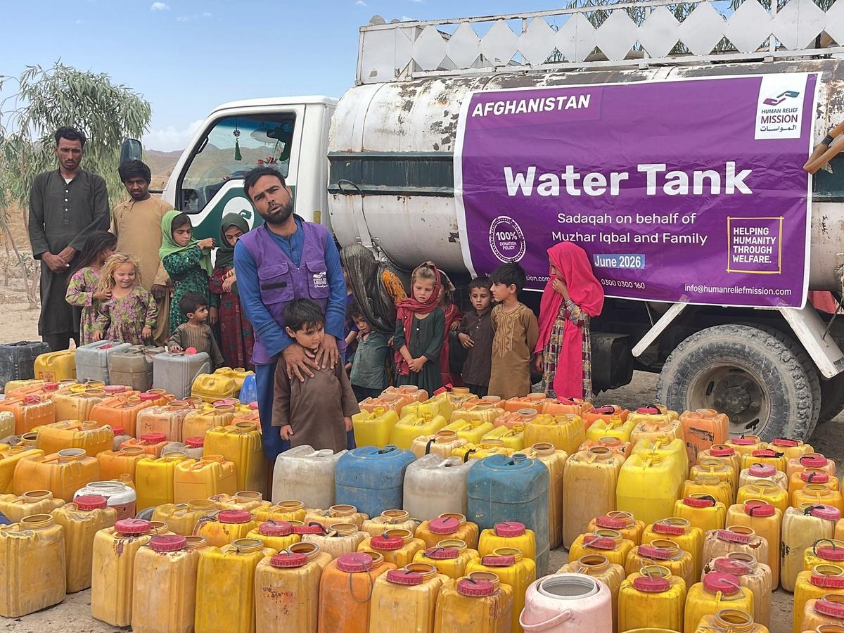 Families in Afghanistan with HRM Aid Worker next to a Water tanker and buckets | Human Relief Mission