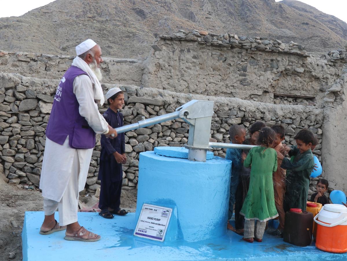 Children and HRM Aid worker with a handpump in Afghanistan | Human Relief Mission