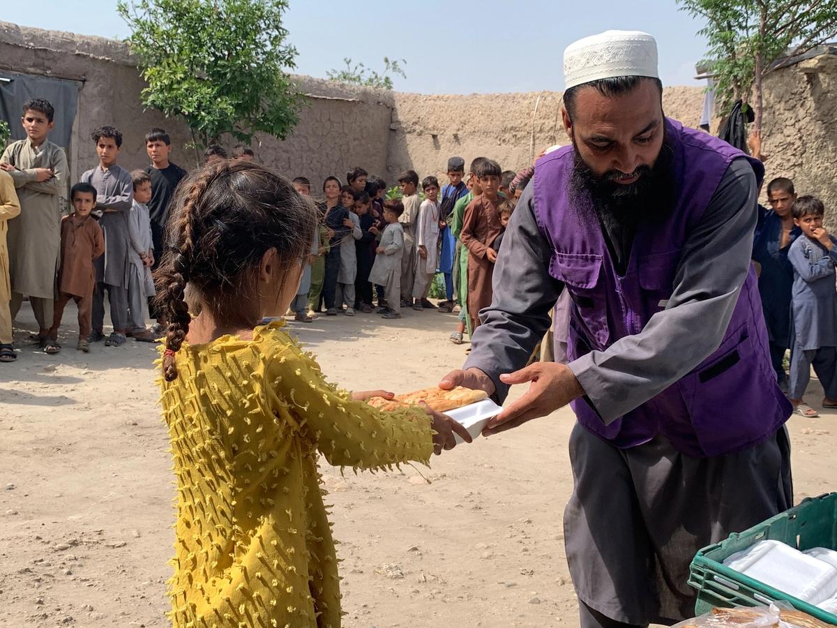 HRM Charity Aid Worker distributing hot meal to a little girl | Human Relief Mission
