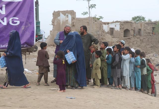 Families receiving a case of water bottles from HRM Aid Worker | Human Relief Mission