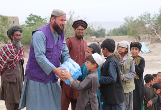 Child receiving a case of water bottles from HRM Aid Worker | Human Relief Mission