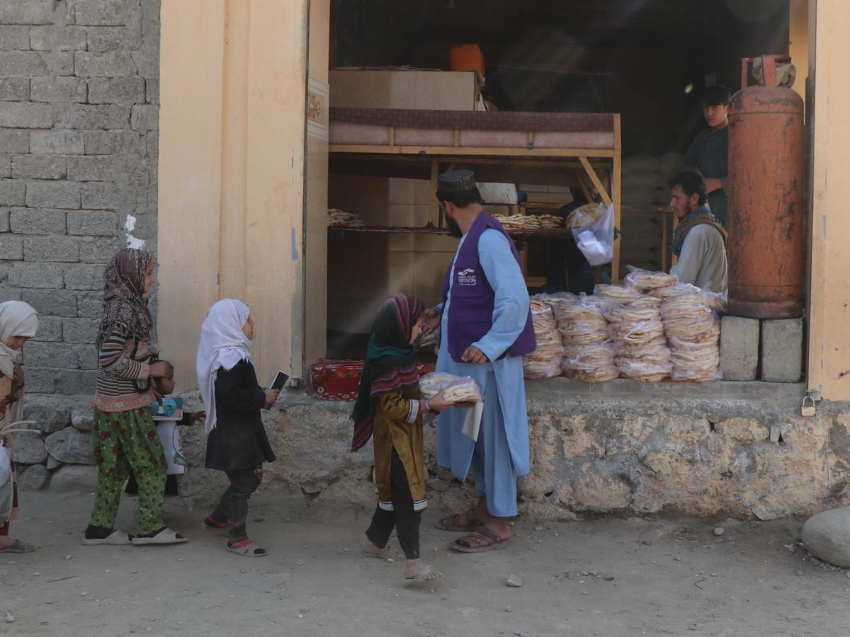 HRM Charity Aid Worker distributing fresh bread to girls outside the Bakery in Afghanistan | Human Relief Mission