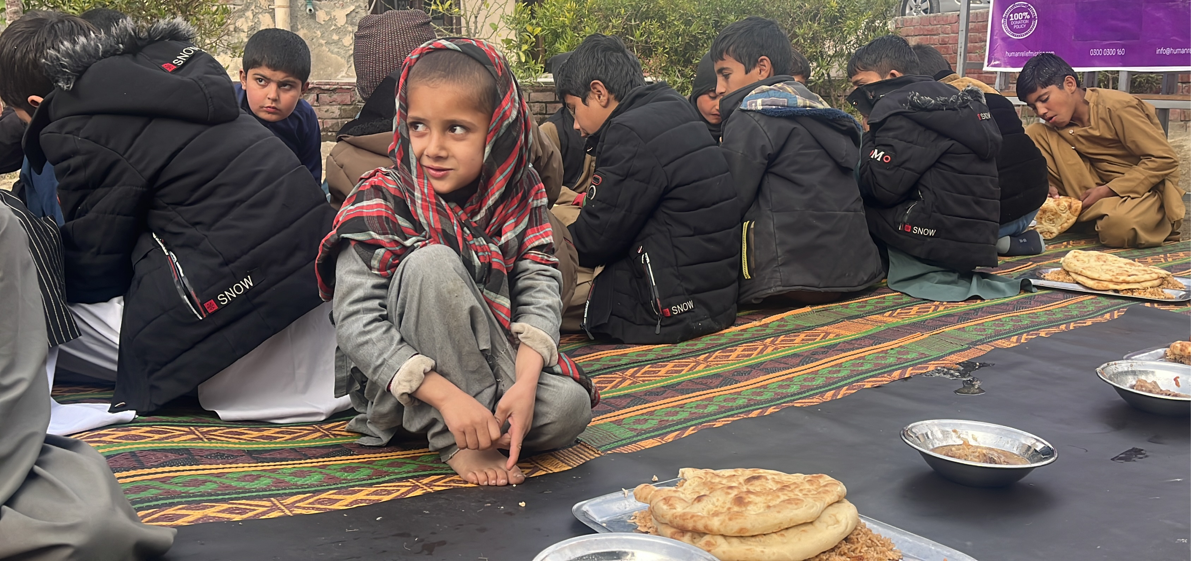 Afghan child eating food sitting on the floor