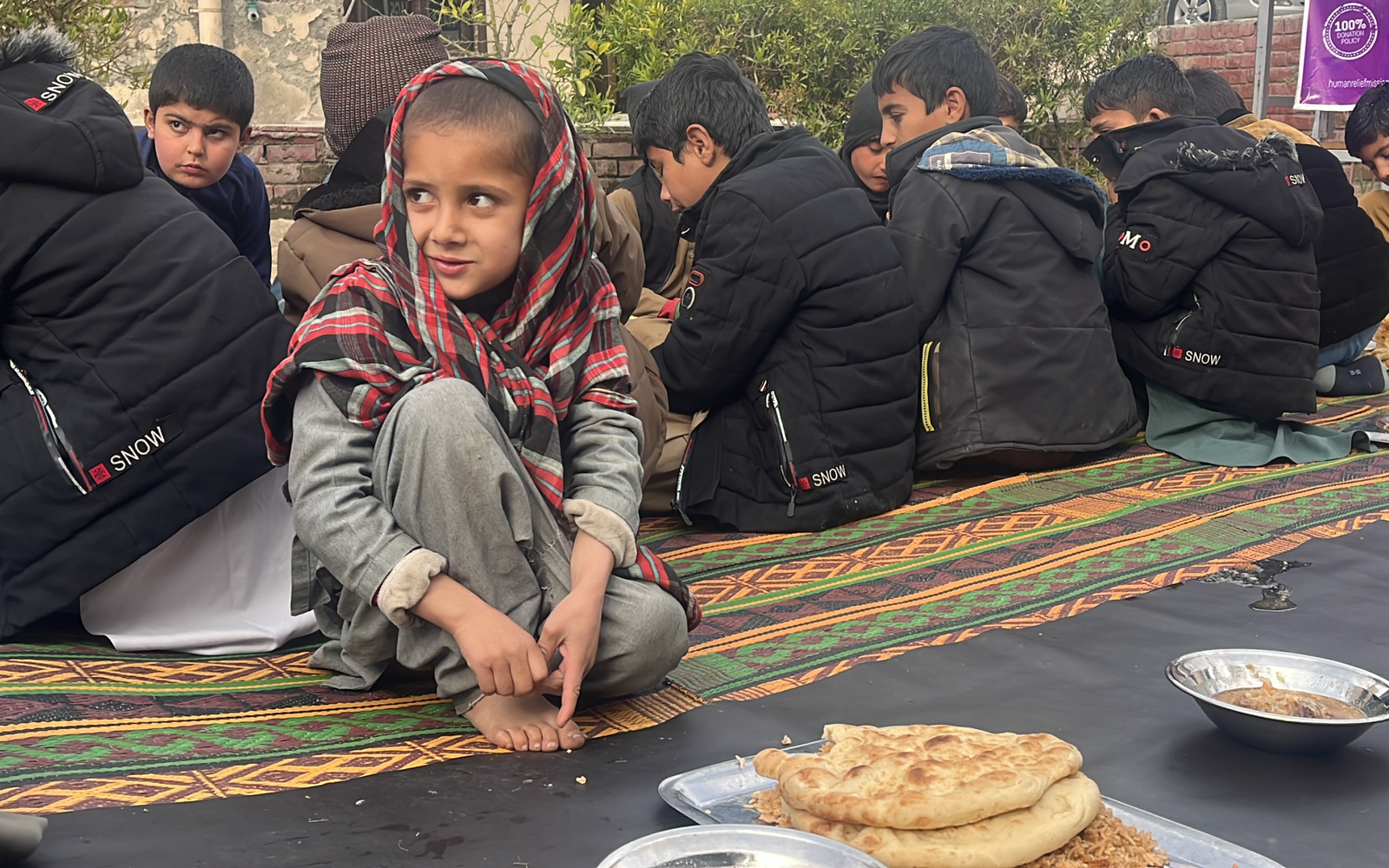 Afghan child eating food sitting on the floor