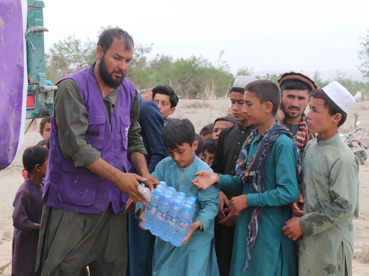 Afghan Children receiving a case of water bottles | Human Relief Mission
