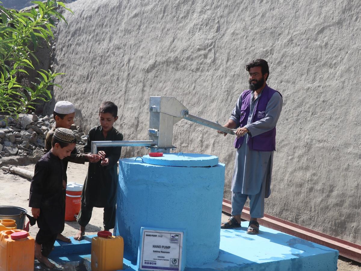 Children and HRM Aid Worker with a handpump in Afghanistan | Human Relief Mission