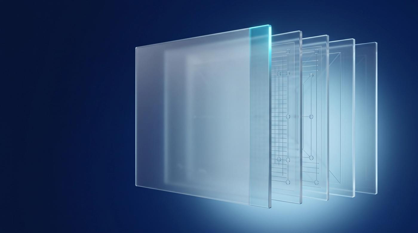 Layered translucent glass panels fanned apart, revealing an ordered internal structure behind the front face.