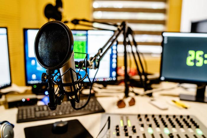 Radio studio desk with condenser microphone, mixing desk and on-air clock