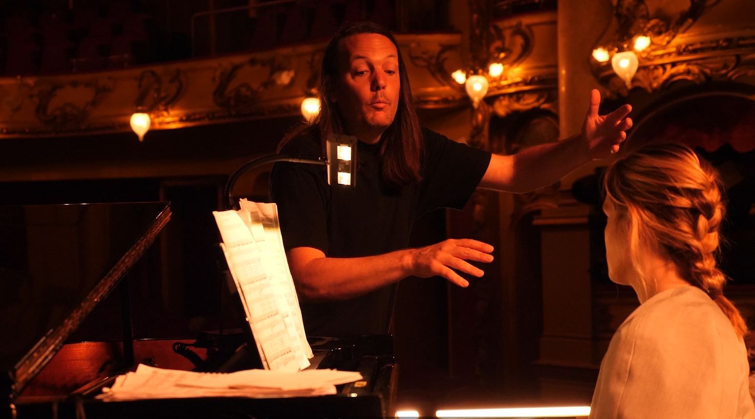 Mann dirigerer pianist på en scene