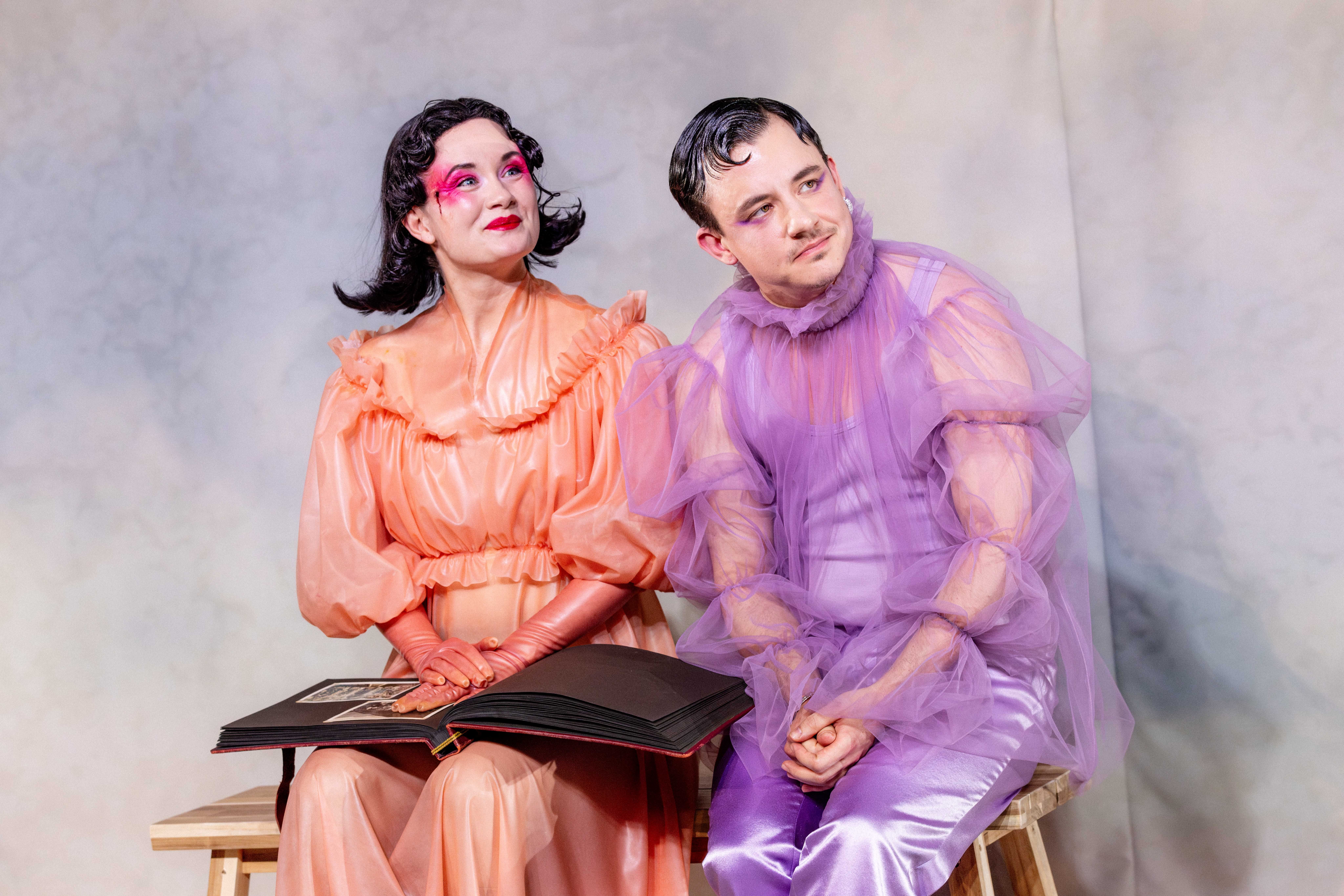 To personer sitter sammen på en benk og ser opp mens en stor fotoalbum ligger åpent i fanget