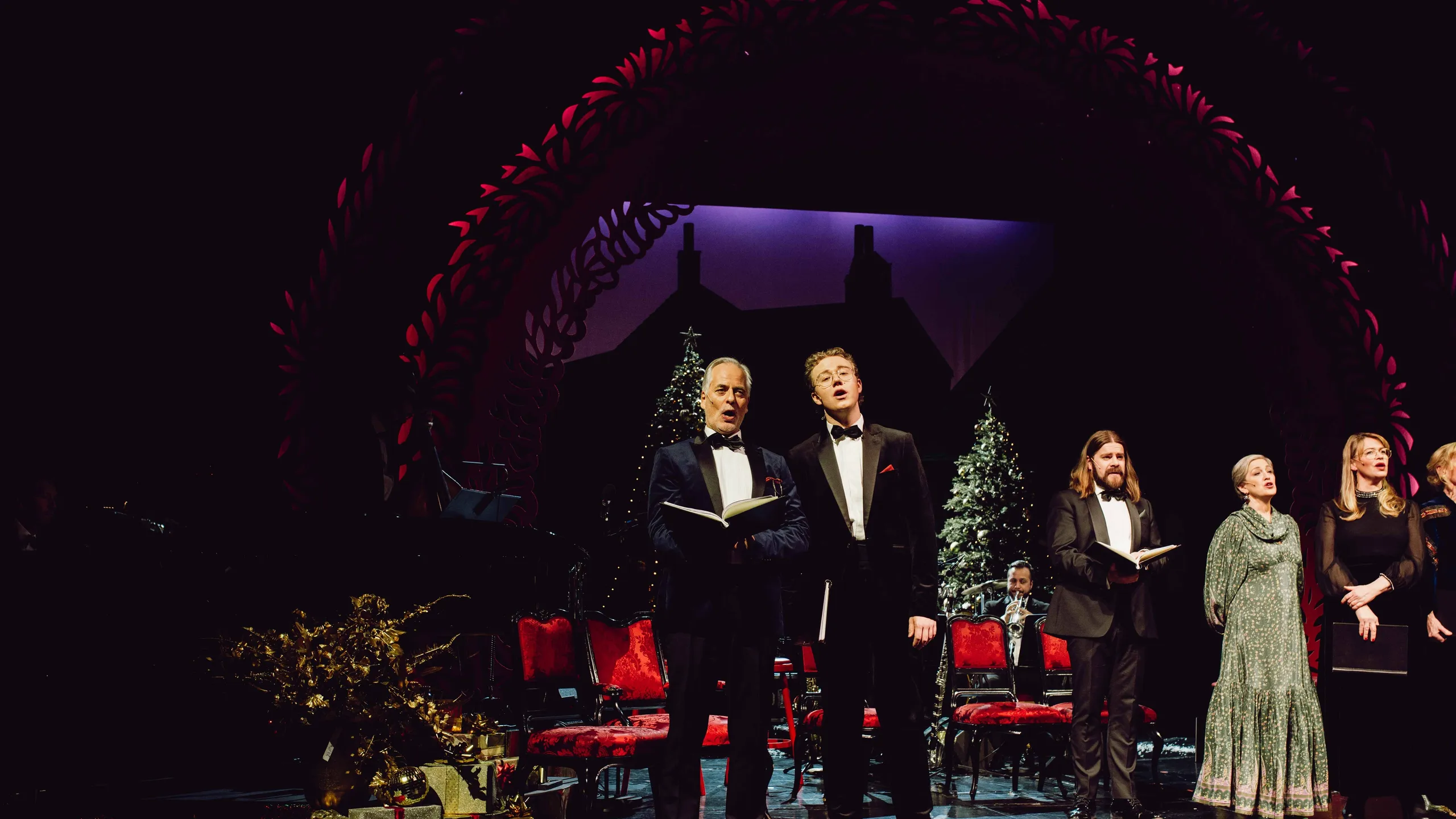 To menn synger på julepyntet scene