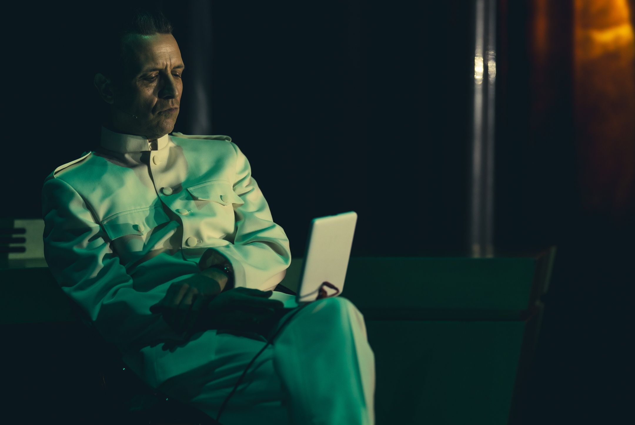 Mann i lys uniform som sitter og ser på noe som ser ut som en skjerm