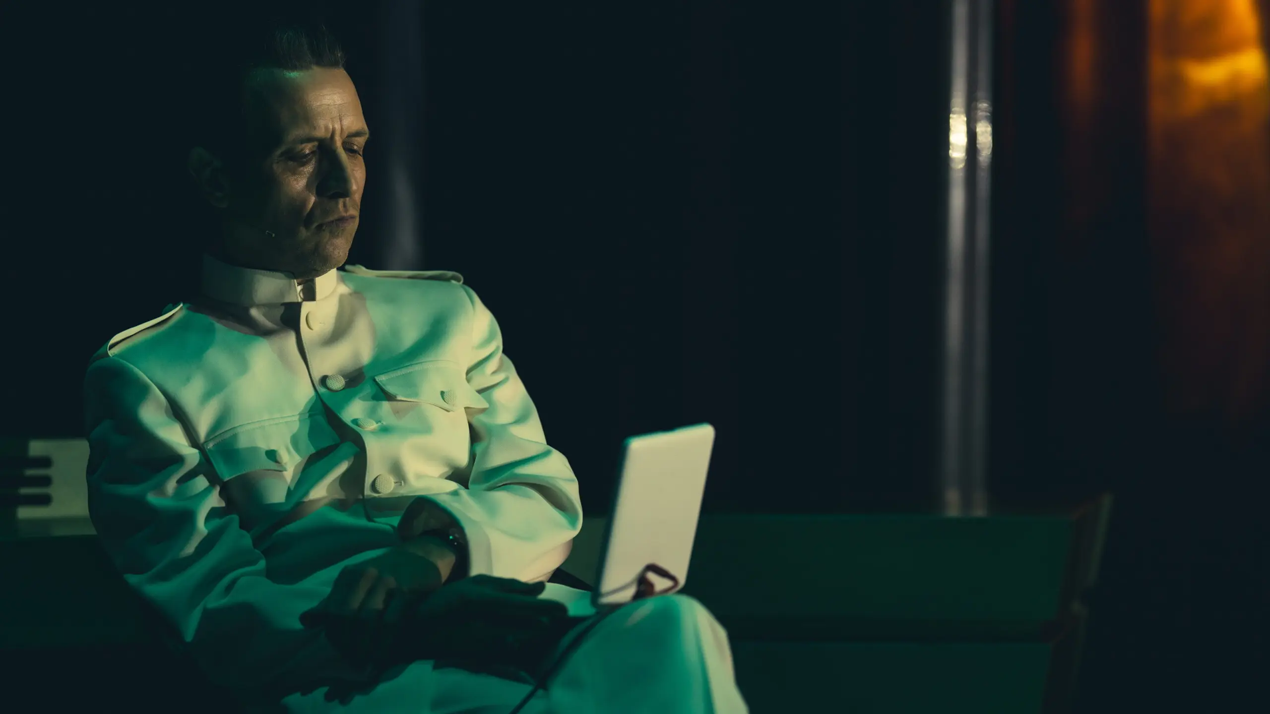 Mann i lys uniform som sitter og ser på noe som ser ut som en skjerm