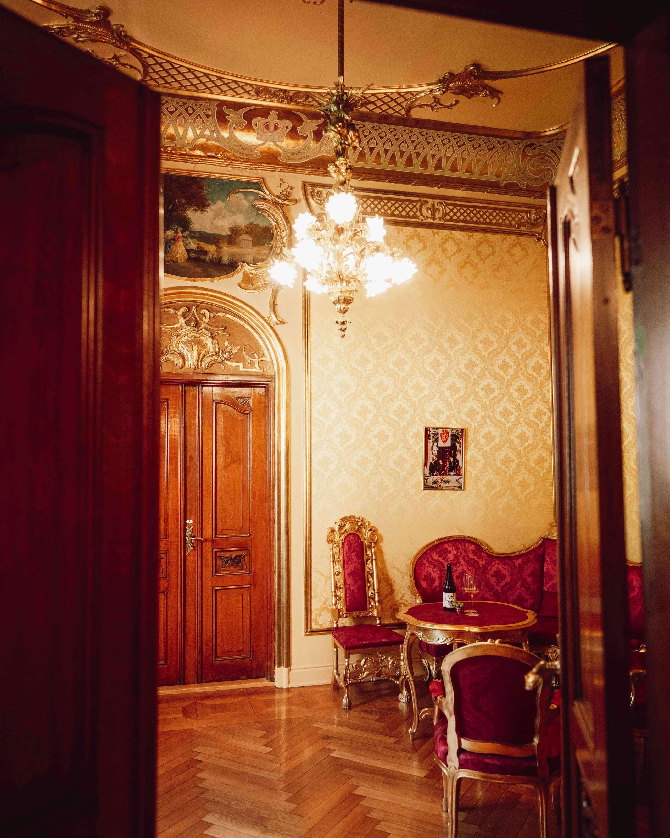 Interiørbilde fra Kongelosjen på Nationaltheatret med lysekrone, forgylte detaljer, historiske møbler og sittegruppe.