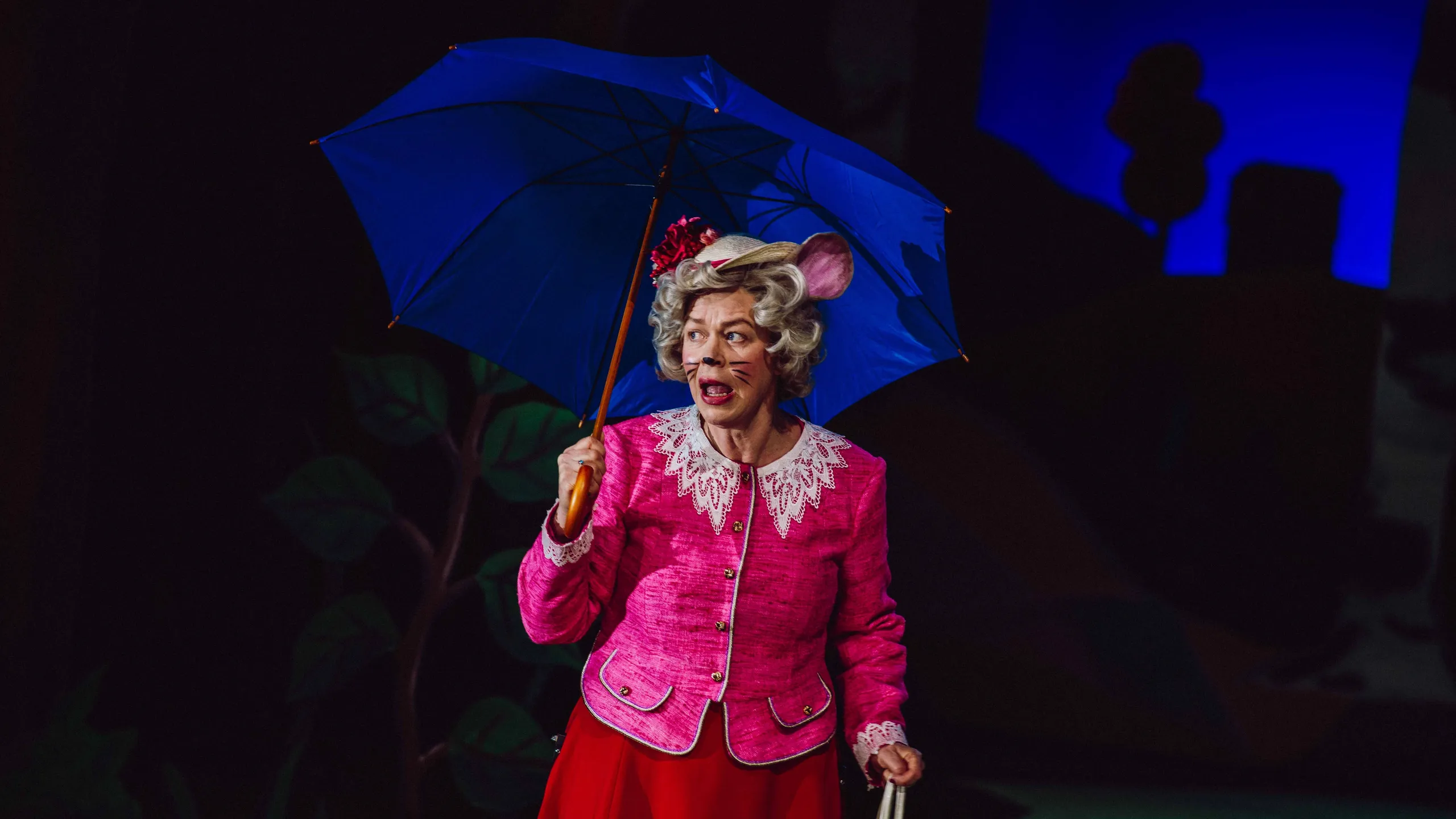 Person i rosa drakt med museører og blå paraply