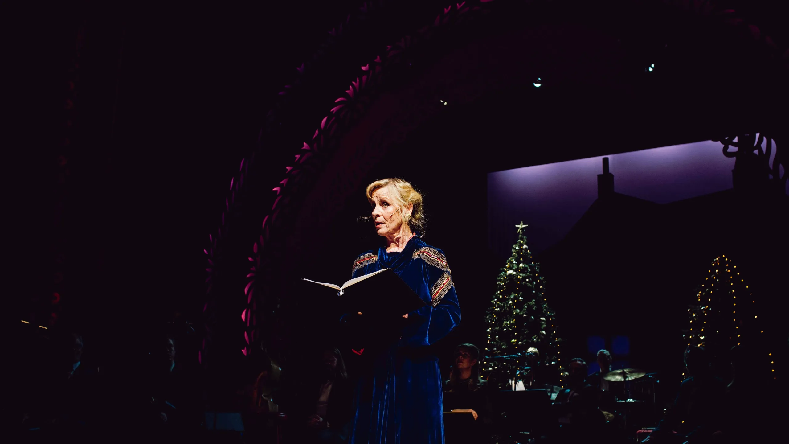 Kvinne leser fra bok på julepyntet scene