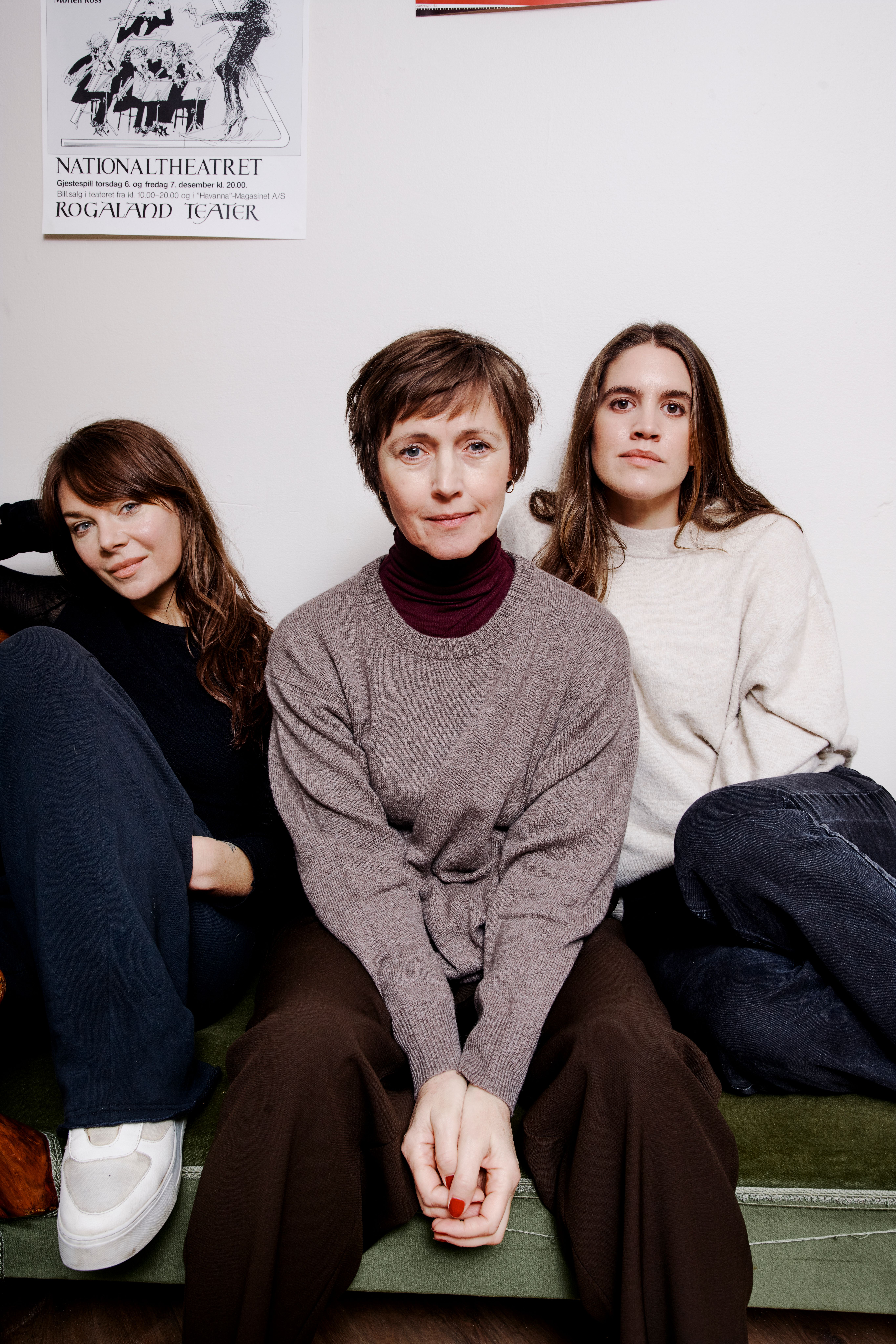 Tre kvinner sitter i en grønn sofa mot en hvit vegg