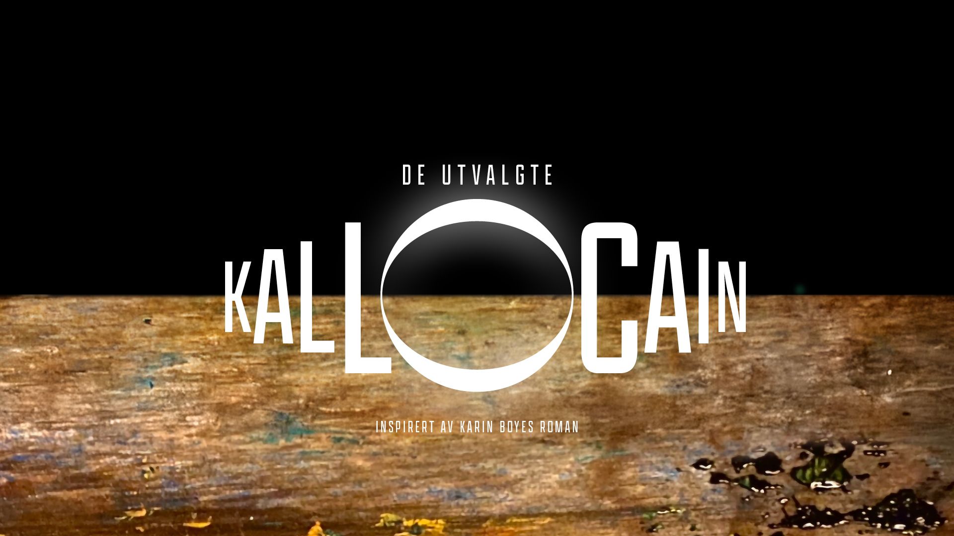 Noe som kan minne om en brun jordskorpe med dråper på mot svart himmel, med tekst De Utvalgte Kallocain inspirert av Karin Boyes roman