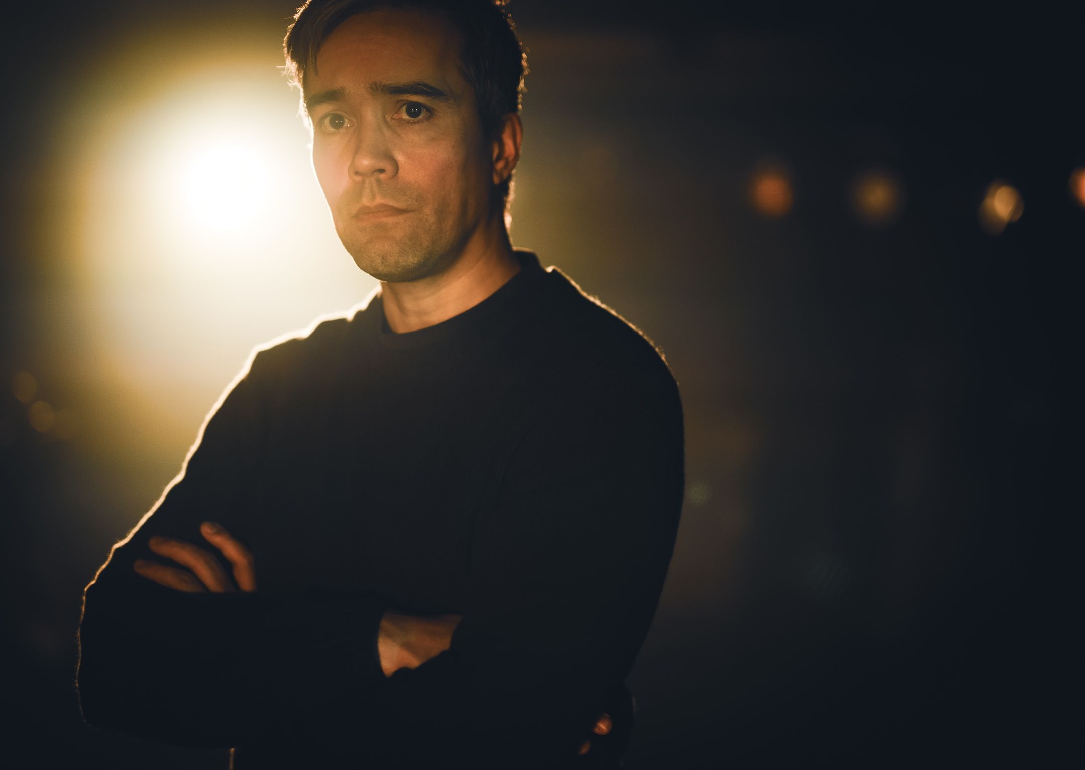 Alvorlig mann med armene i kryss med sterkt baklys