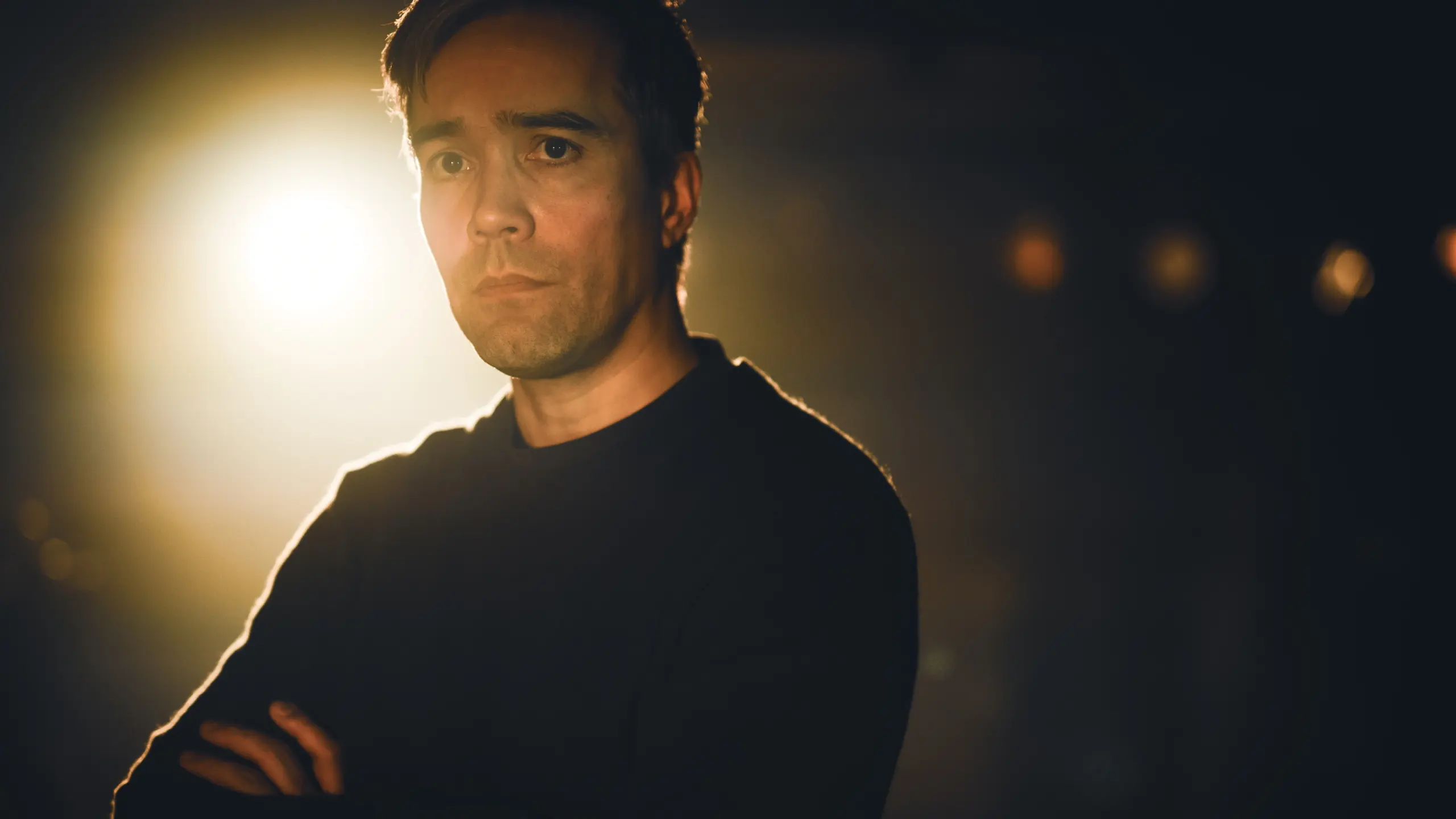 Alvorlig mann med armene i kryss med sterkt baklys