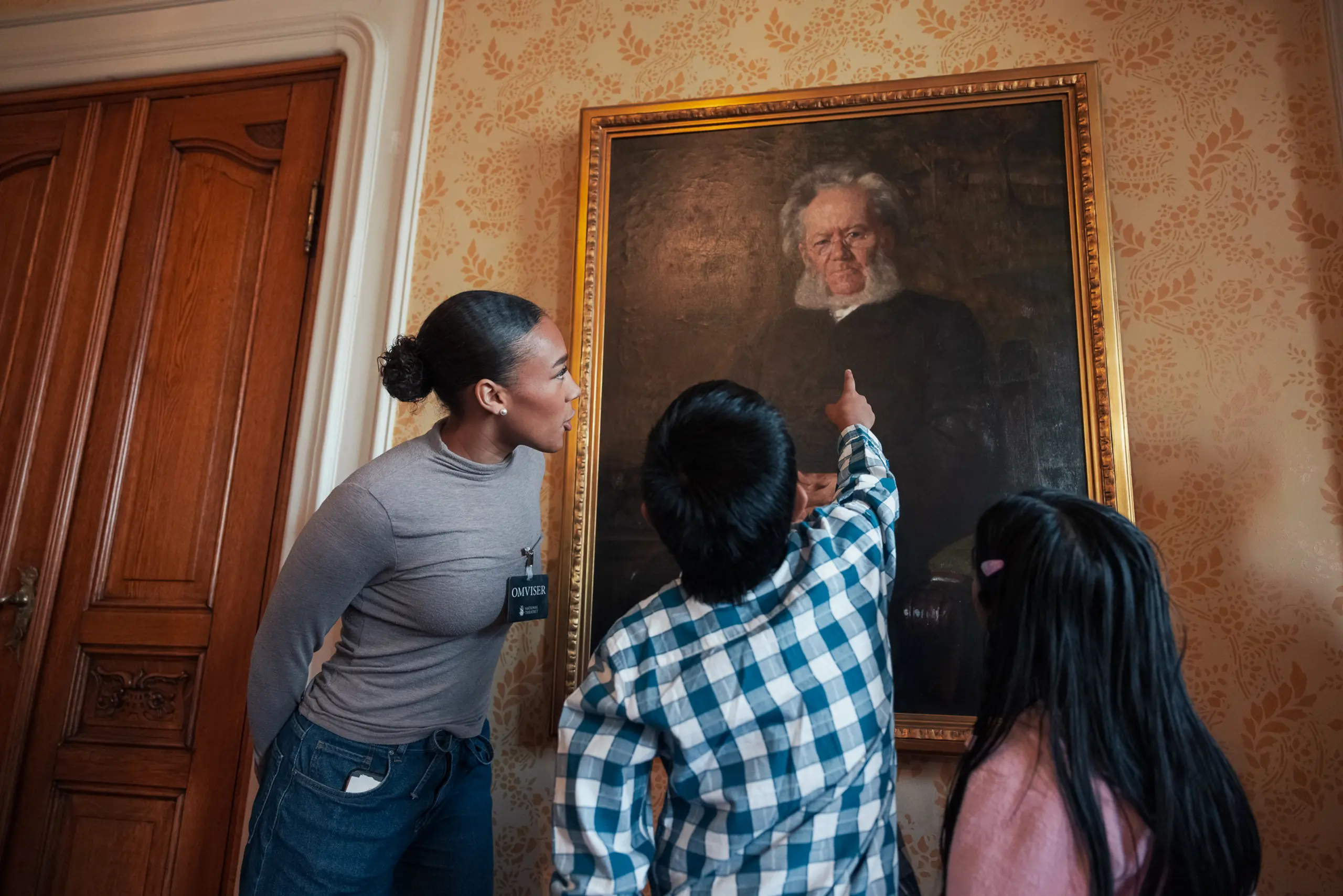 Barn peker på et maleri av Henrik Ibsen mens omviser og annen elev ser på.