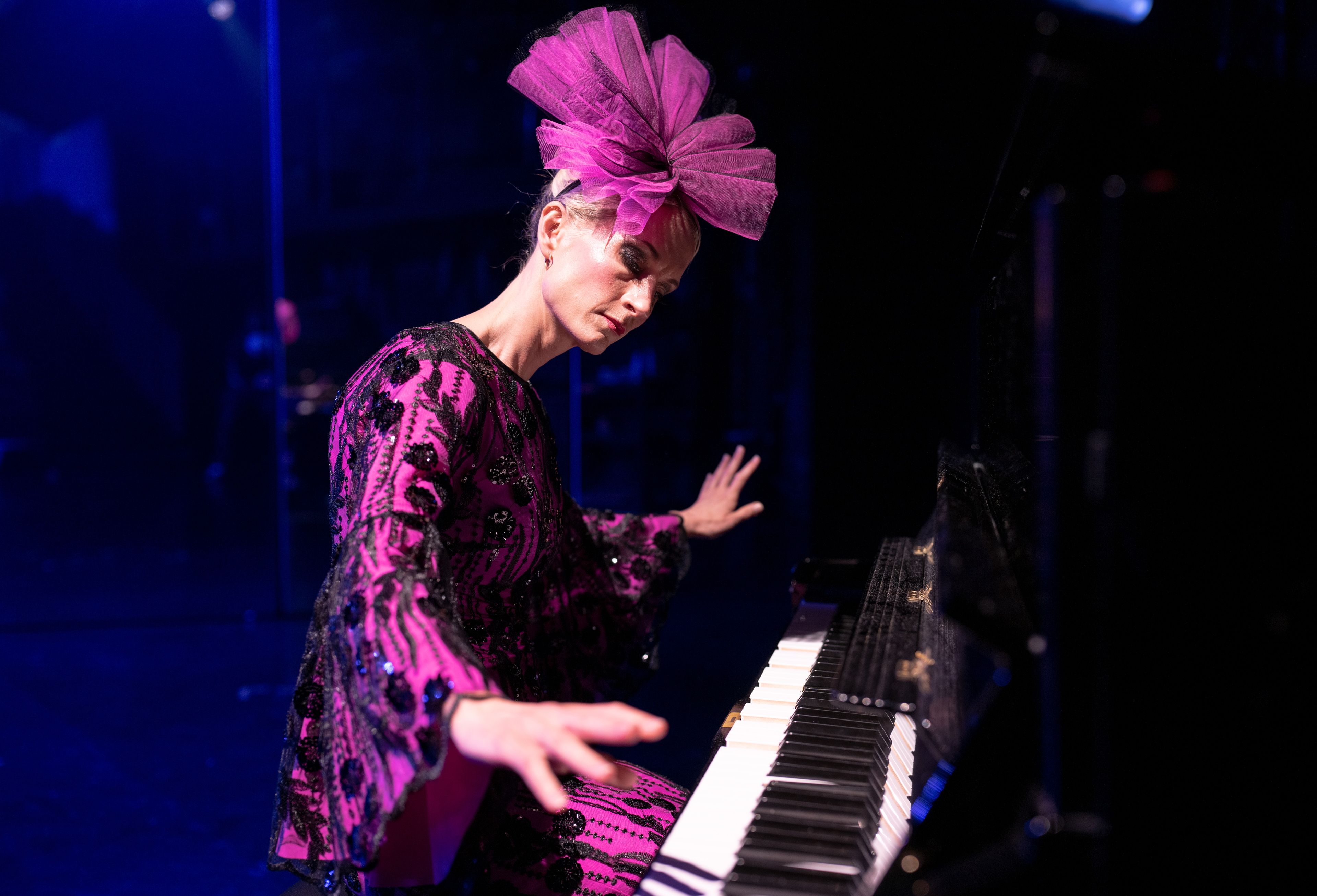 Kvinne i rosa kostyme og rosa sløyfe på hodet spiller piano
