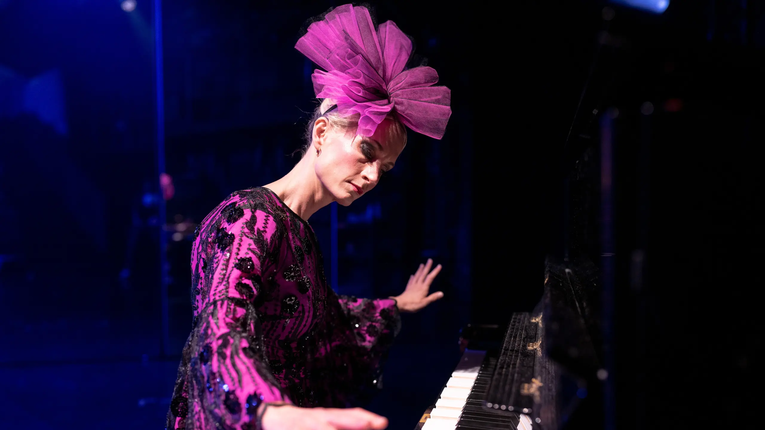 Kvinne i rosa kostyme og rosa sløyfe på hodet spiller piano