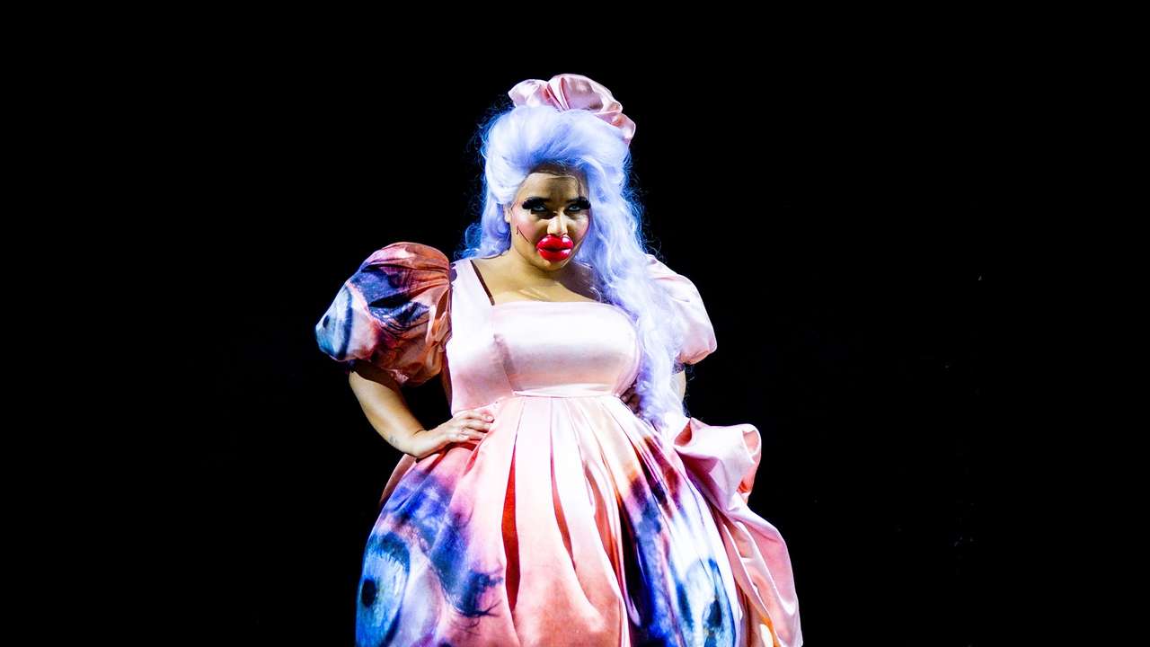 Kvinne i overdrevet teatersminke og rosa kjole med øye på