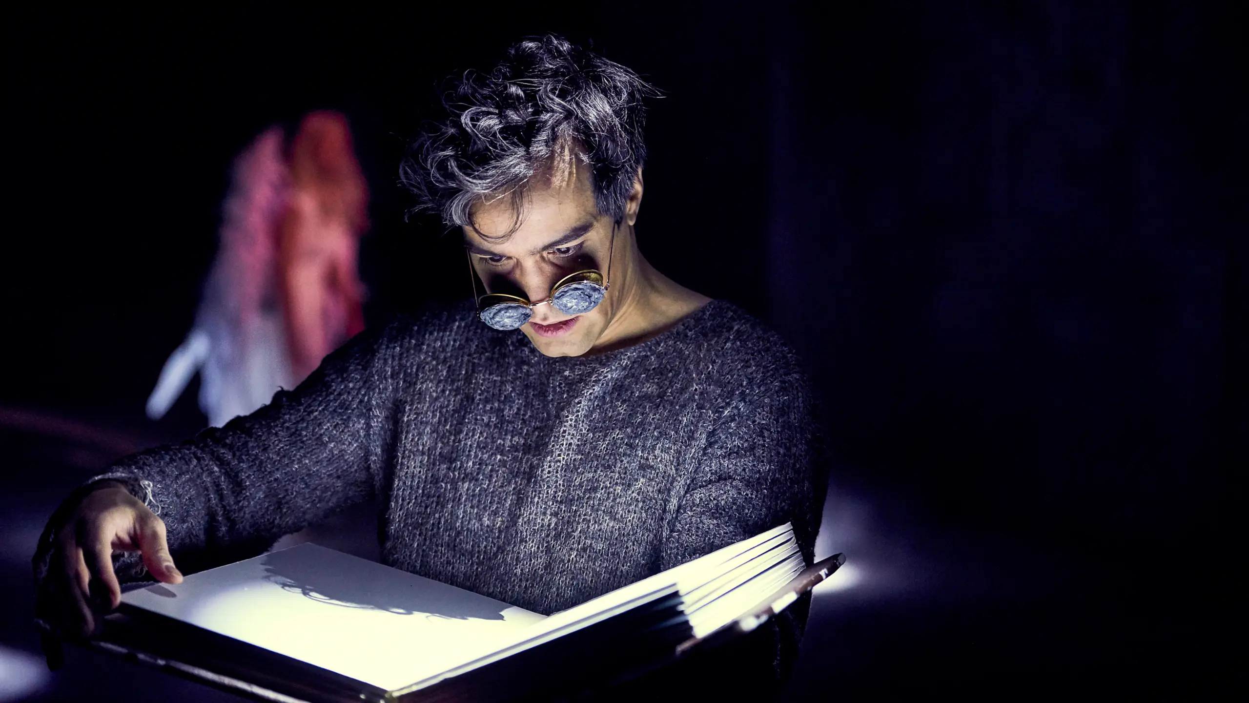 Hermann Sabado som leser i en stor bok i Engler i Amerika