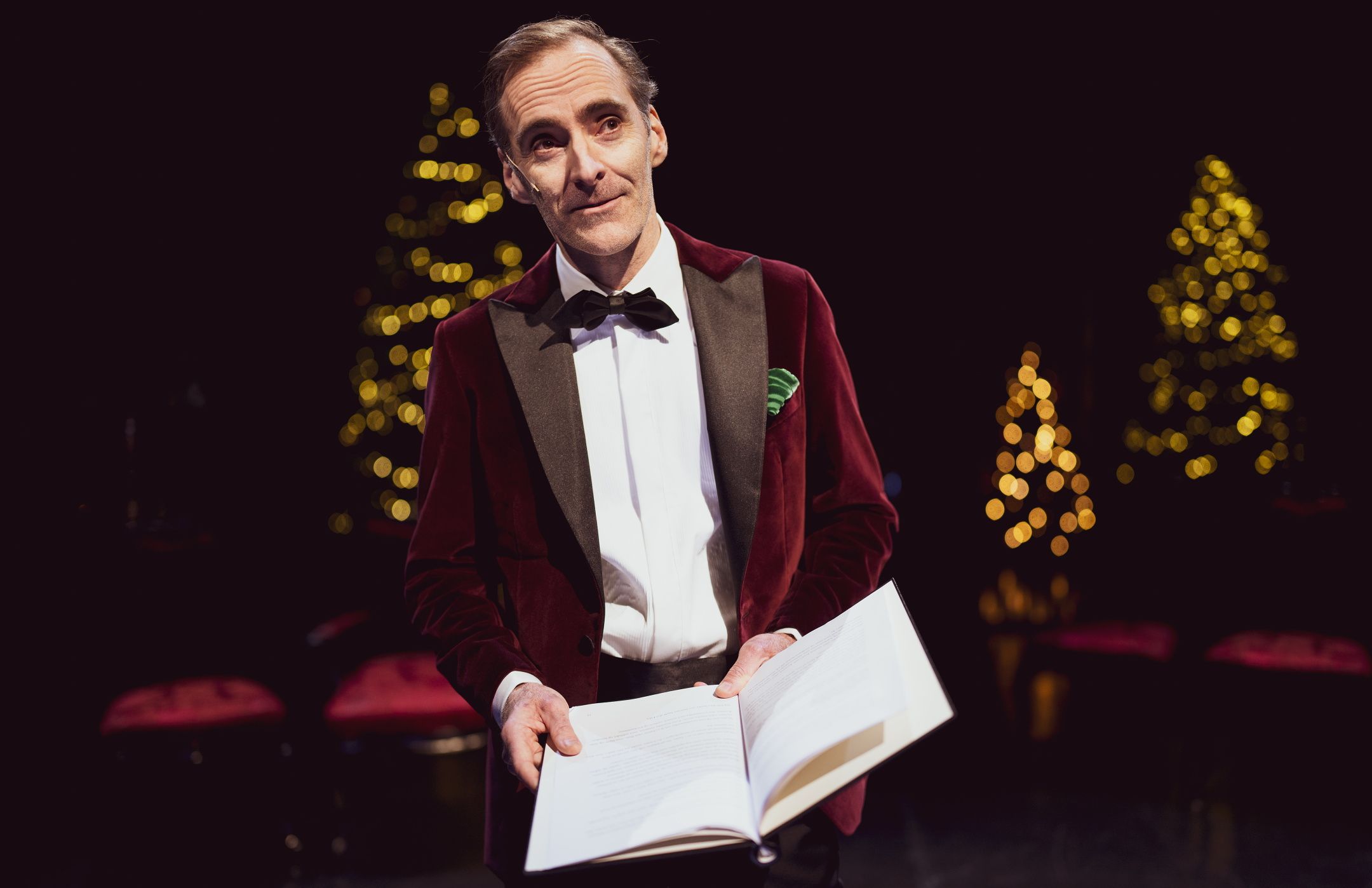 Mann i smoking som leser fra en bok