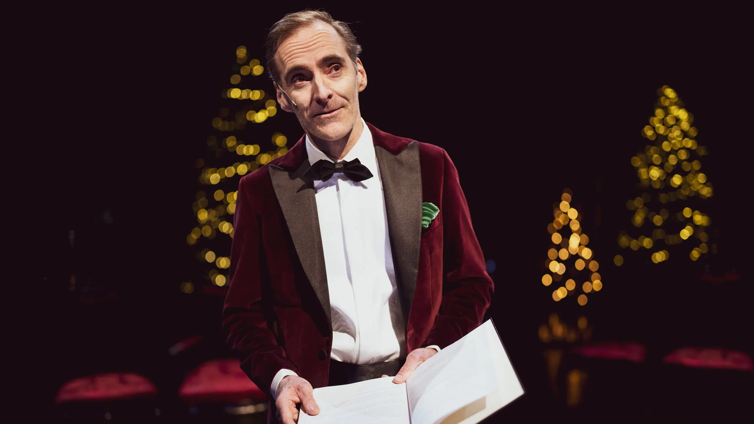 Mann i smoking som leser fra en bok