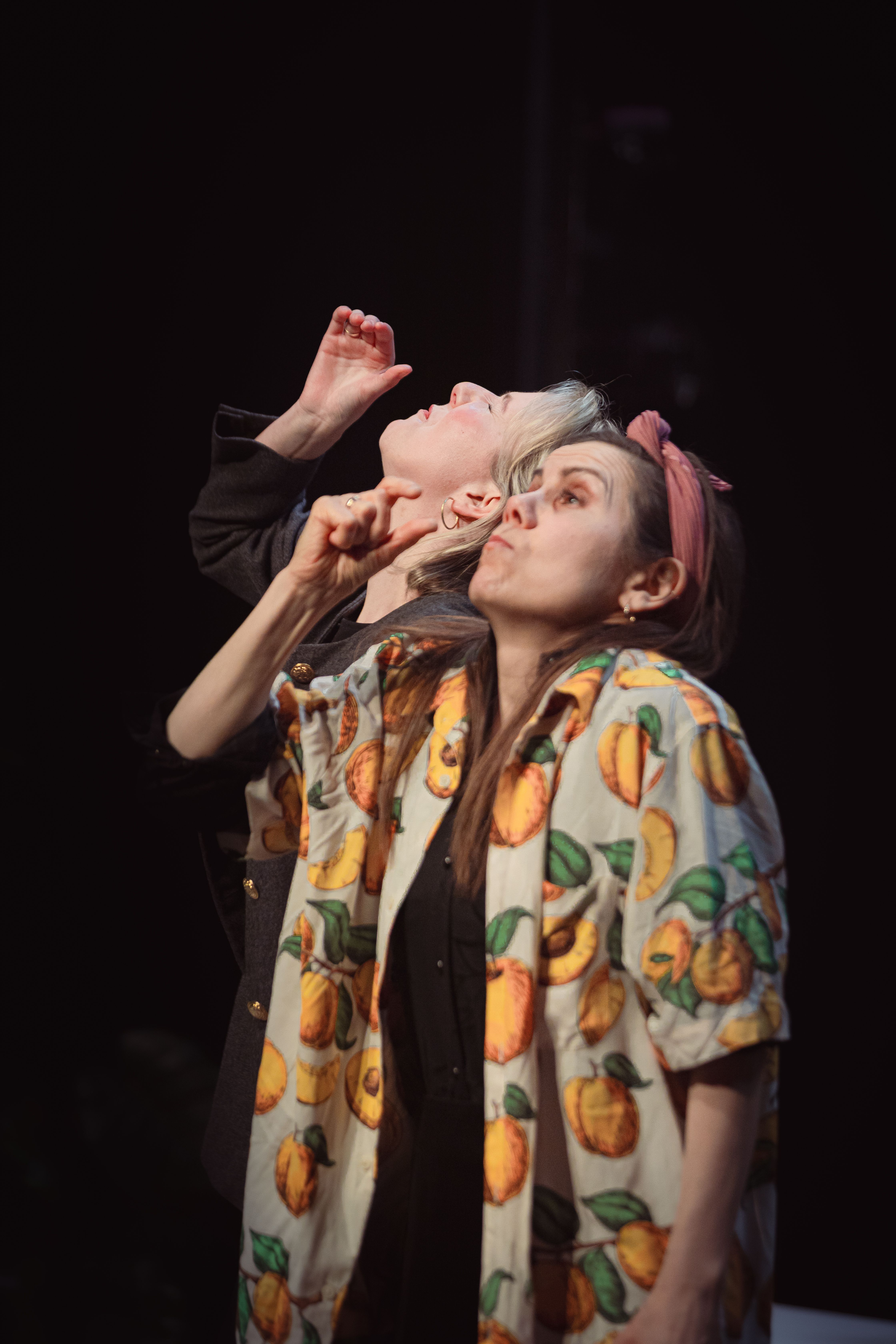 To personer ser oppover og peker, én i skjorte med fruktmønster og én med kort lyst hår