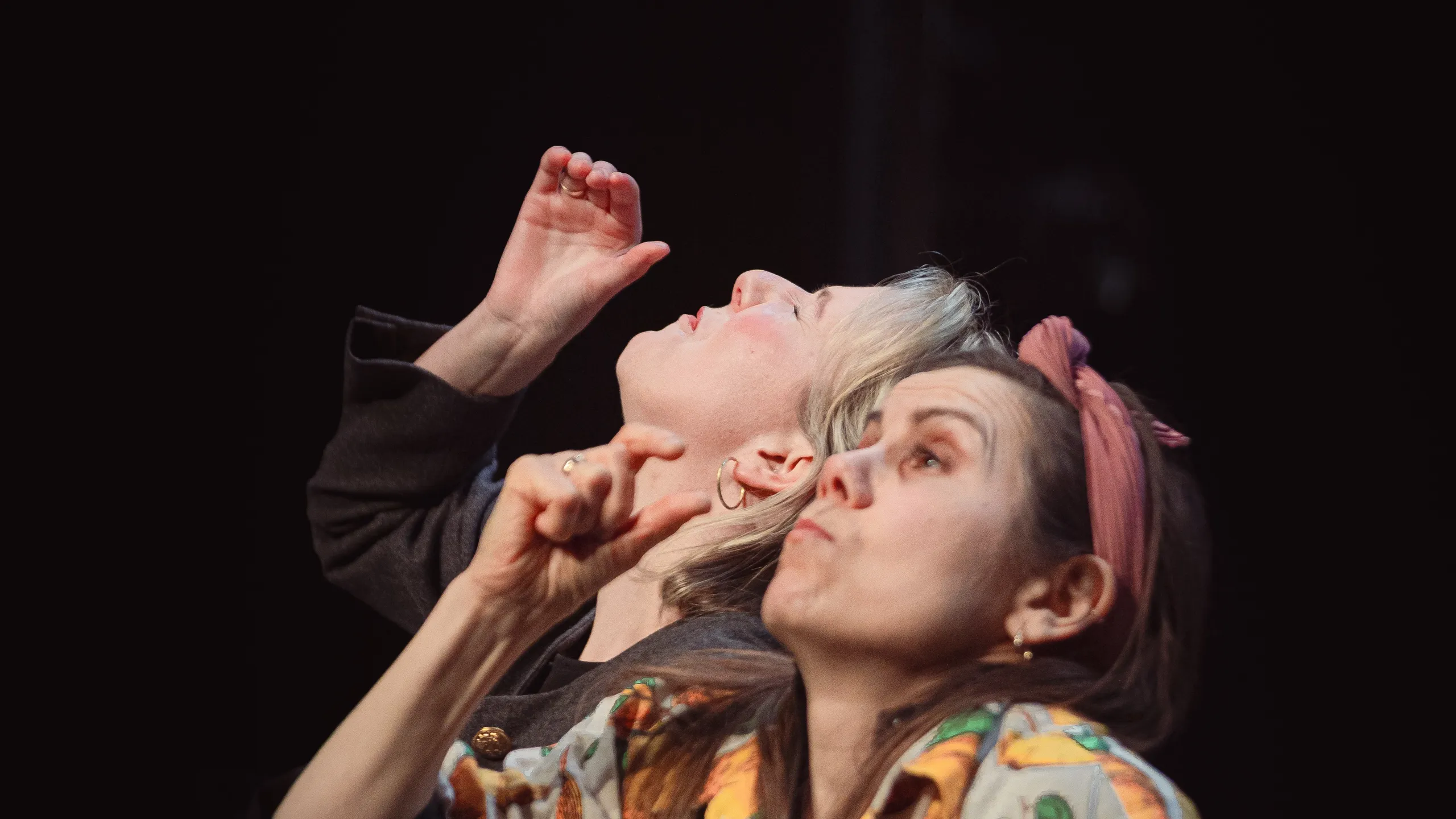 To personer ser oppover og peker, én i skjorte med fruktmønster og én med kort lyst hår