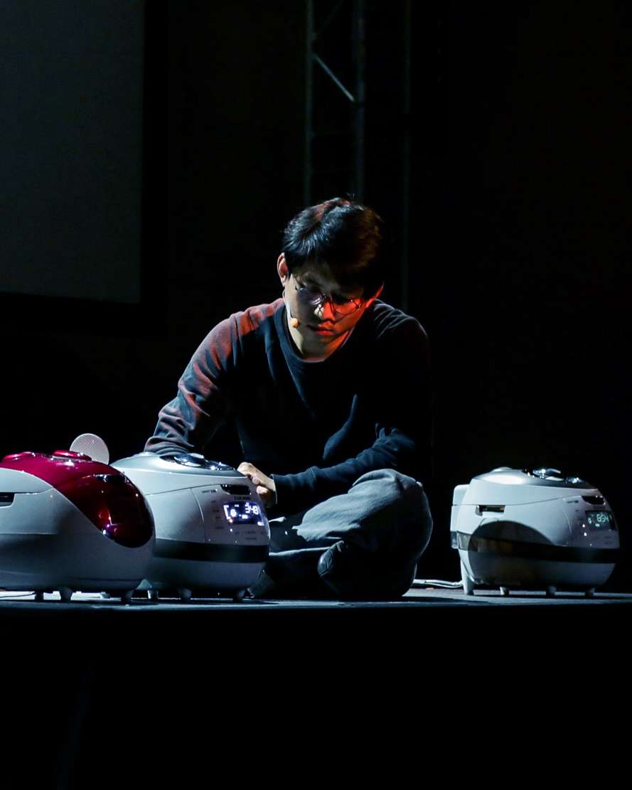 En ung, sørkoreansk mann sitter på scenen sammen med tre riskokere.