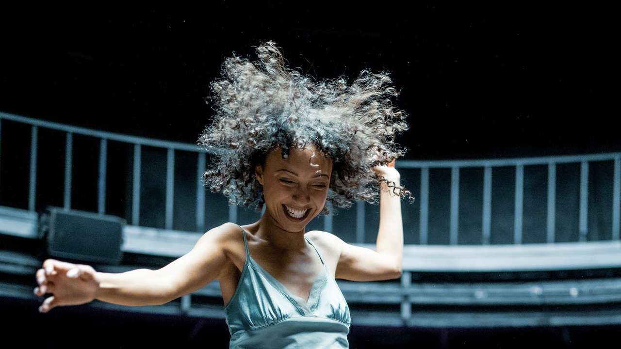 Smilende kvinne som hopper på gul sjeselong, med masse kort på gulvet