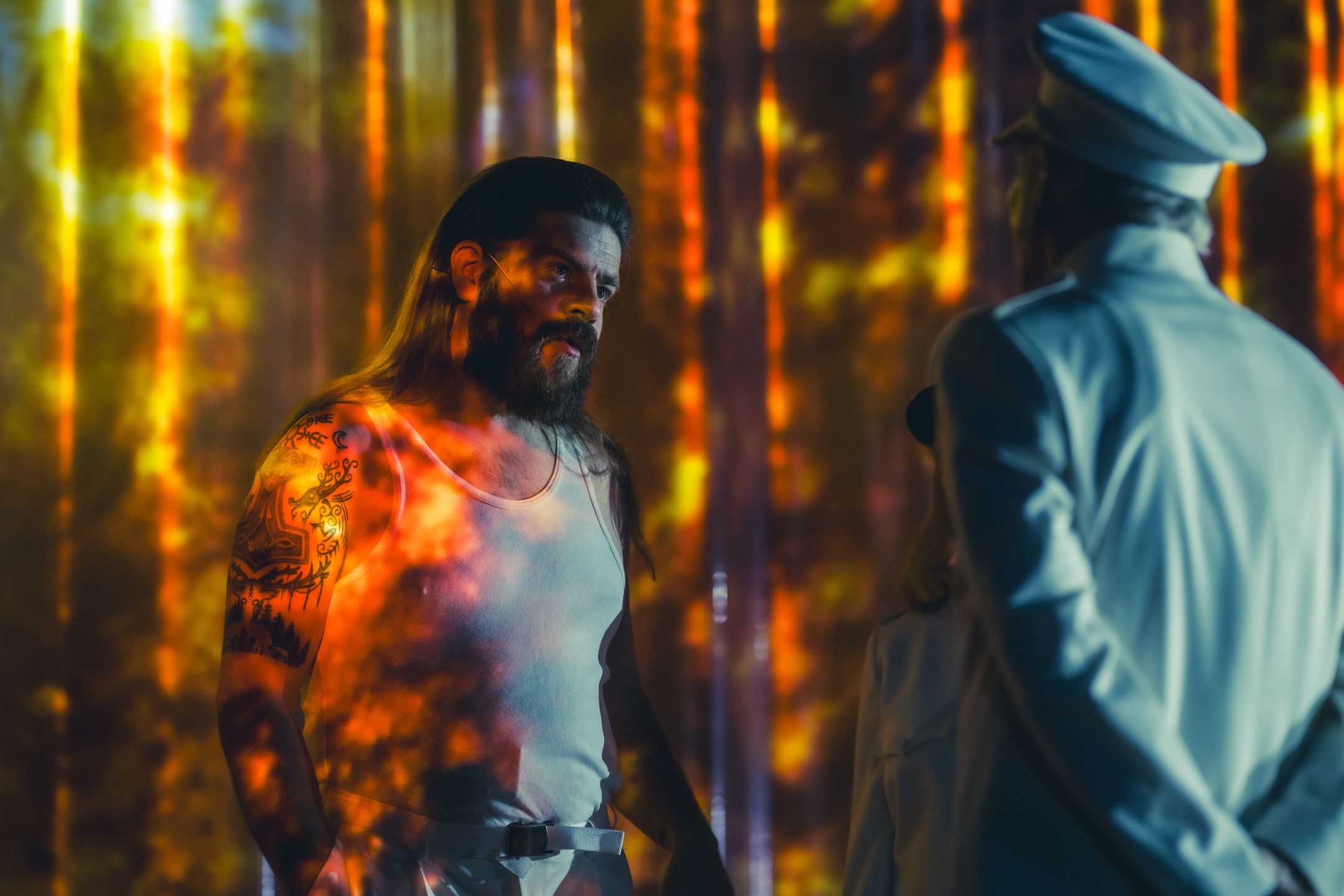 To menn i lys på scene. Den ene i hvit singlet, den andre med uniform