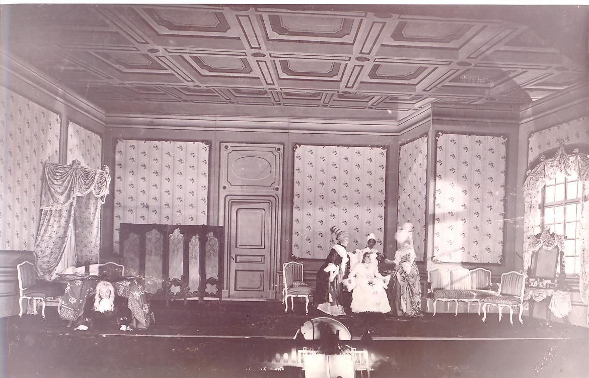 Gammelt bilde av scene som ser ut som en stue