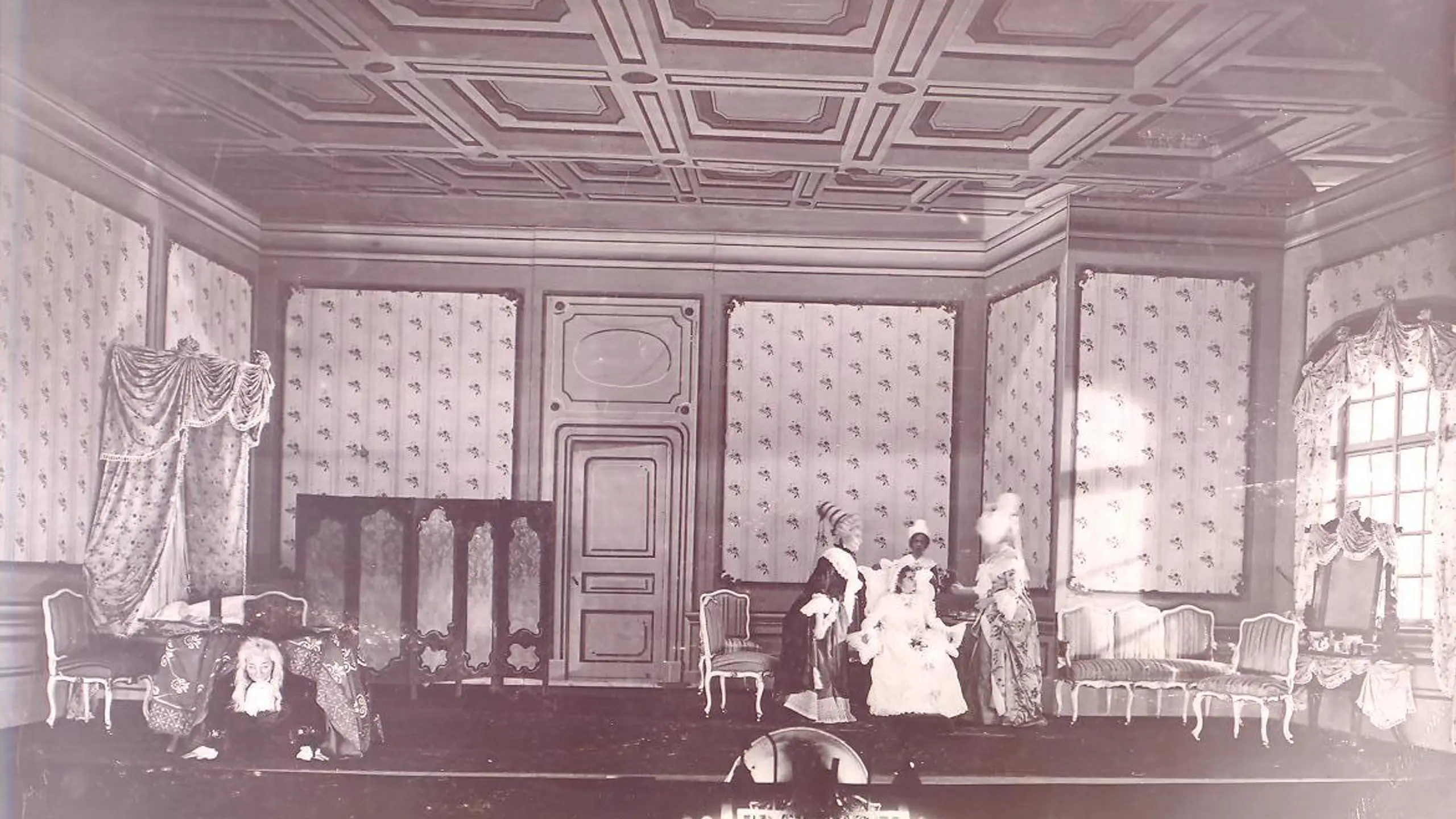 Gammelt bilde av scene som ser ut som en stue