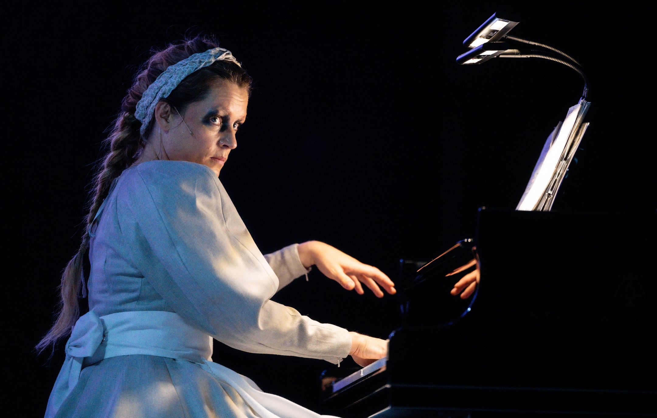 Kvinne med flette og bunadsinspirert kostyme som spiller piano