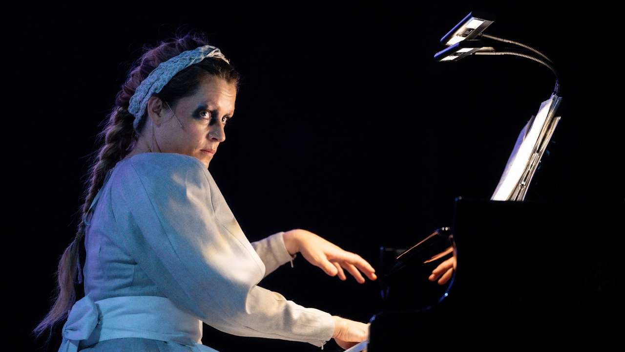 Kvinne med flette og bunadsinspirert kostyme som spiller piano