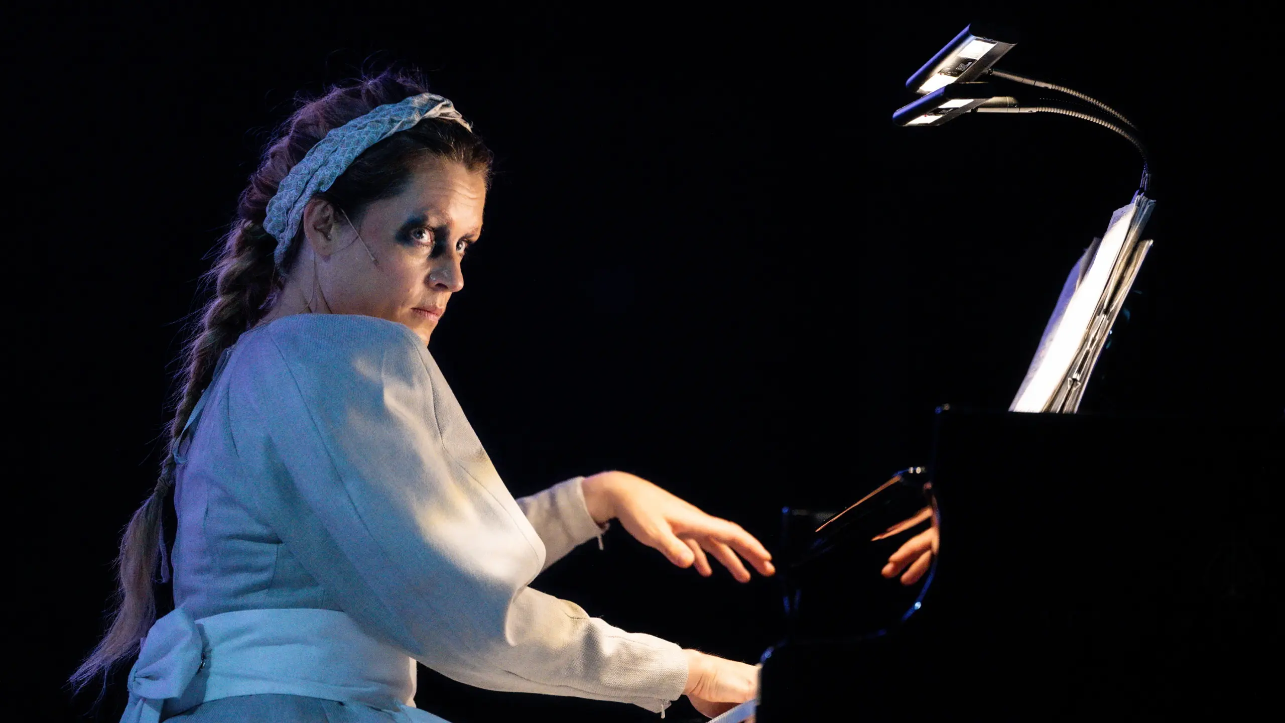 Kvinne med flette og bunadsinspirert kostyme som spiller piano