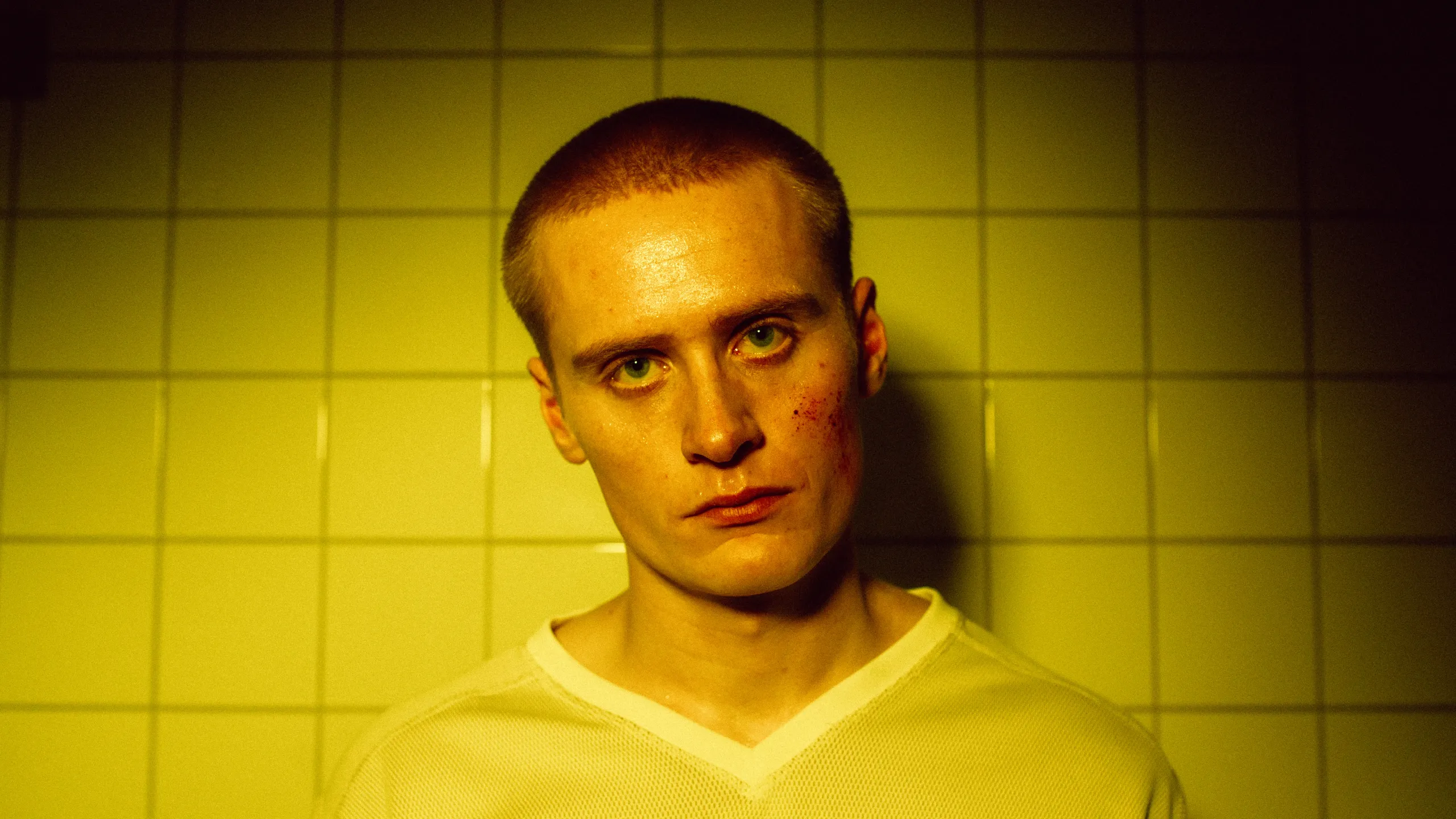 Portrett av mann med blod i fjeset mot gule fliser