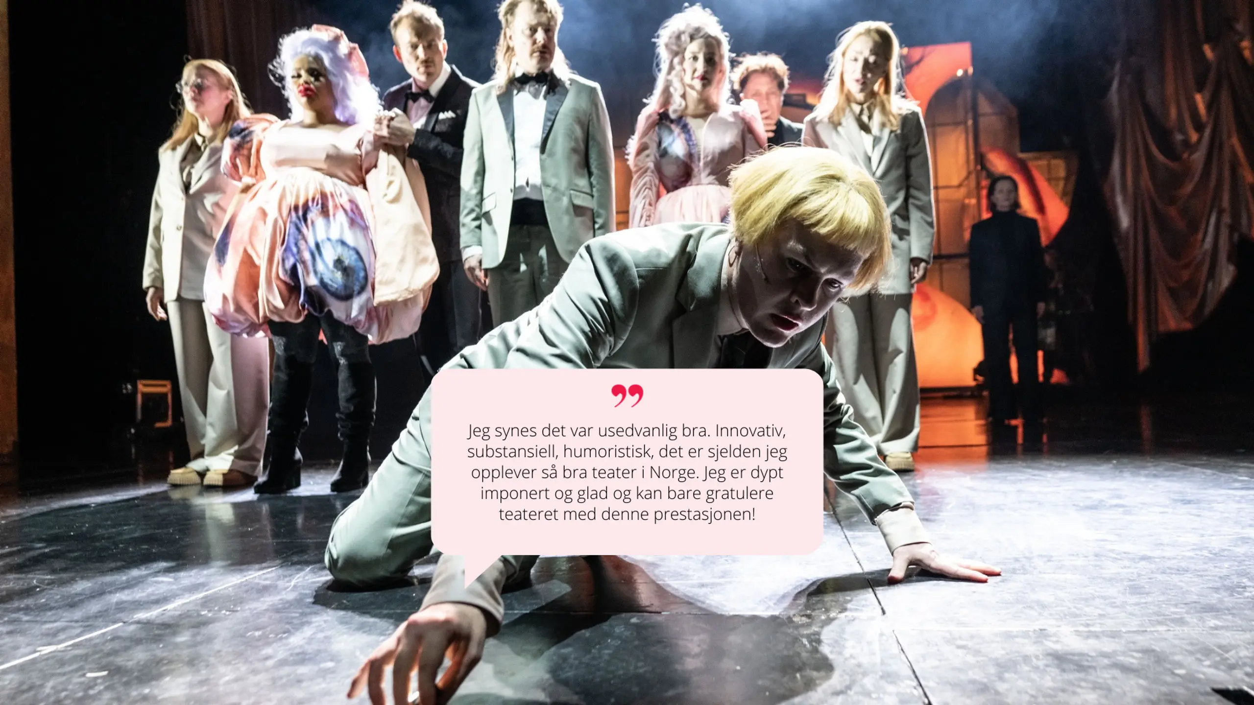 Flere skuespillere på scenen i sterke positurer og kostymer. En av hovedpersonene ligger dramatisk på gulvet i forgrunnen, omgitt av ensemblet.  Sitat i snakkeboble:  "Innovativ, substansiell, humoristisk [...] dypt imponert."