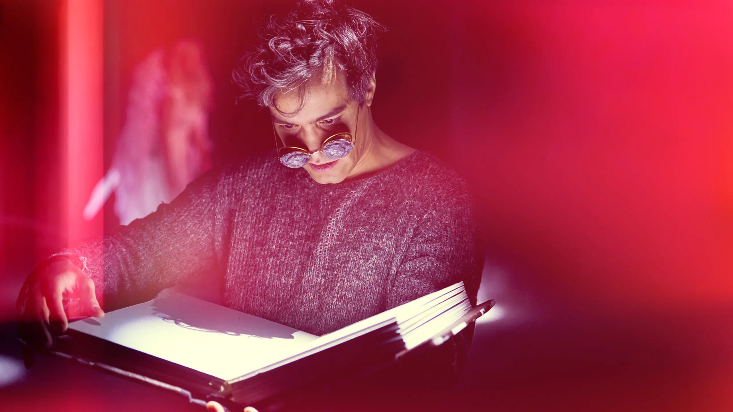 En skuespiller med tykke brilleglass leser i en stor og gammel gammel bok