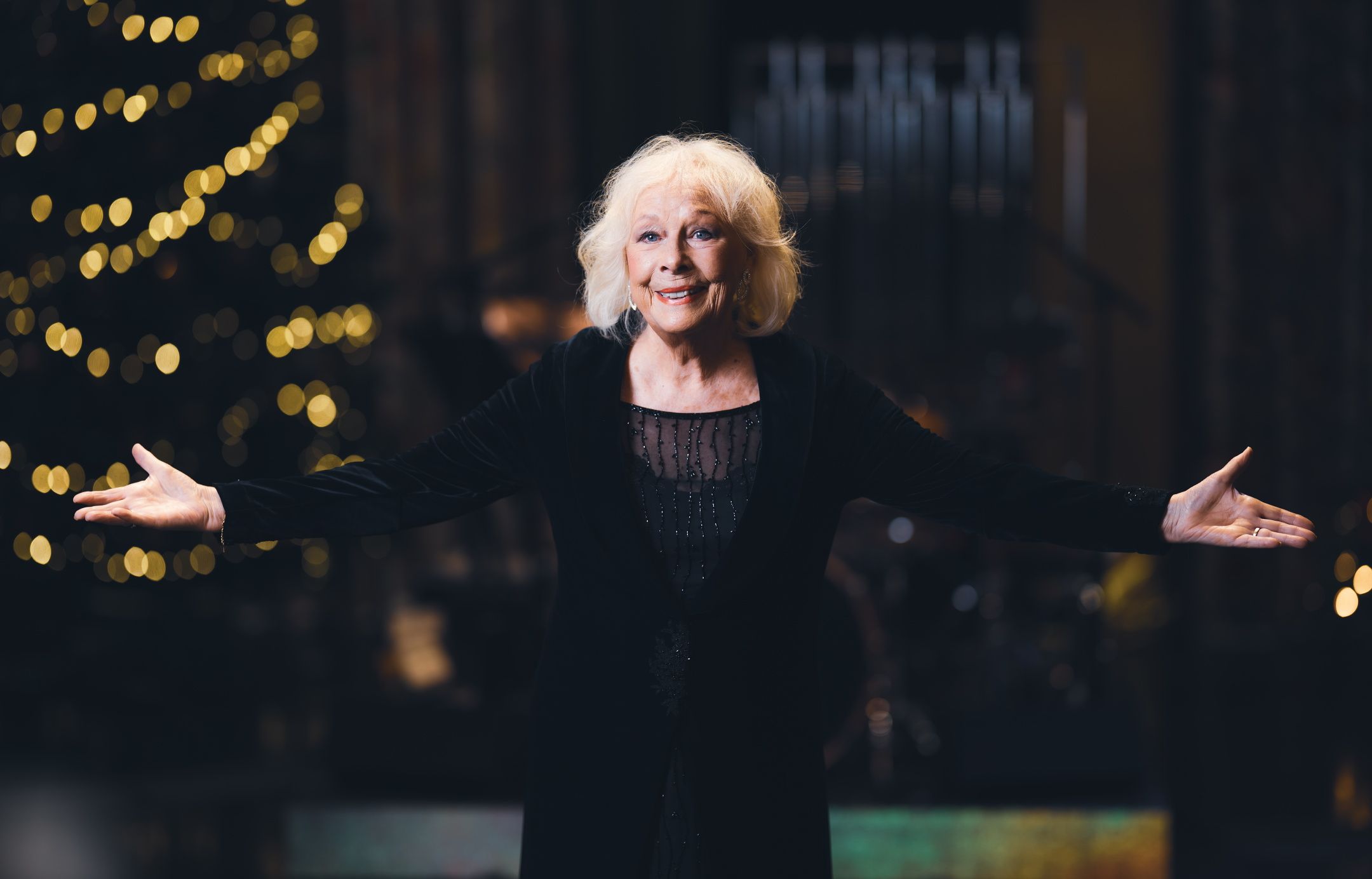 Kvinne på julepyntet scene som holder ut armene