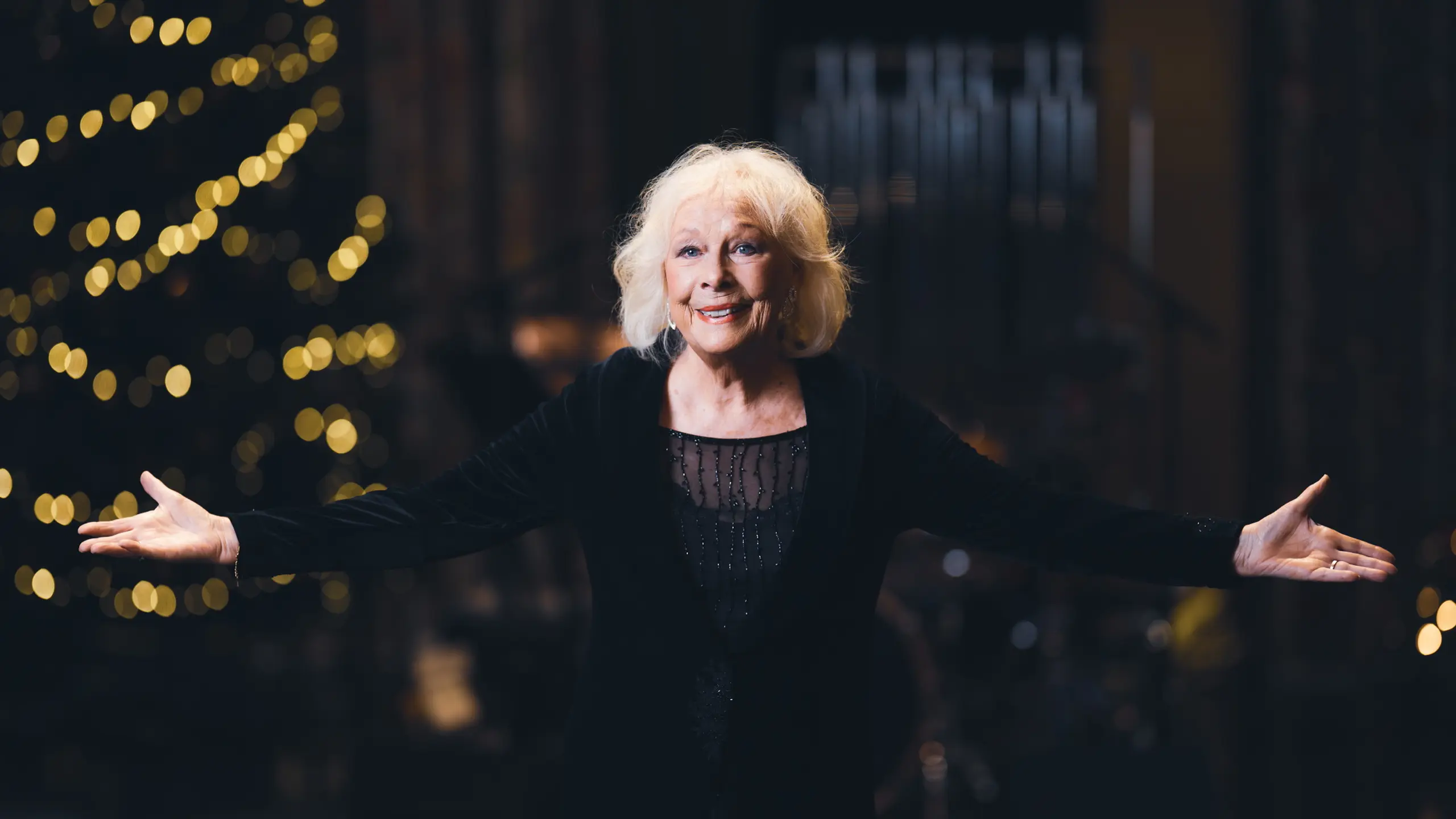 Kvinne på julepyntet scene som holder ut armene