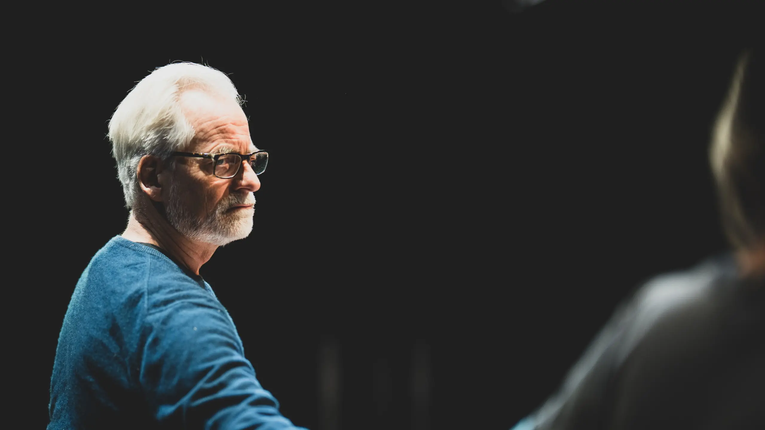 Mann som sitter og ser på en annen person som han holder i hånden