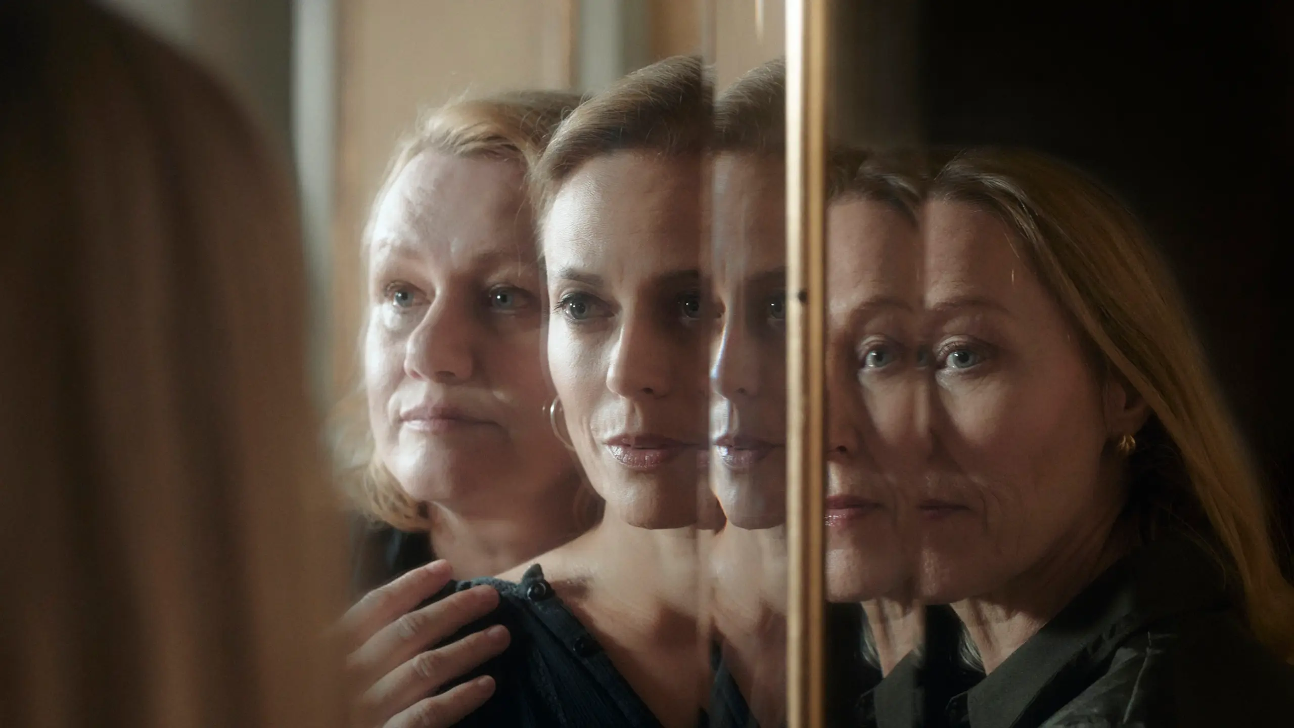 Tre kvinner står foran et speil og holder på hverandre