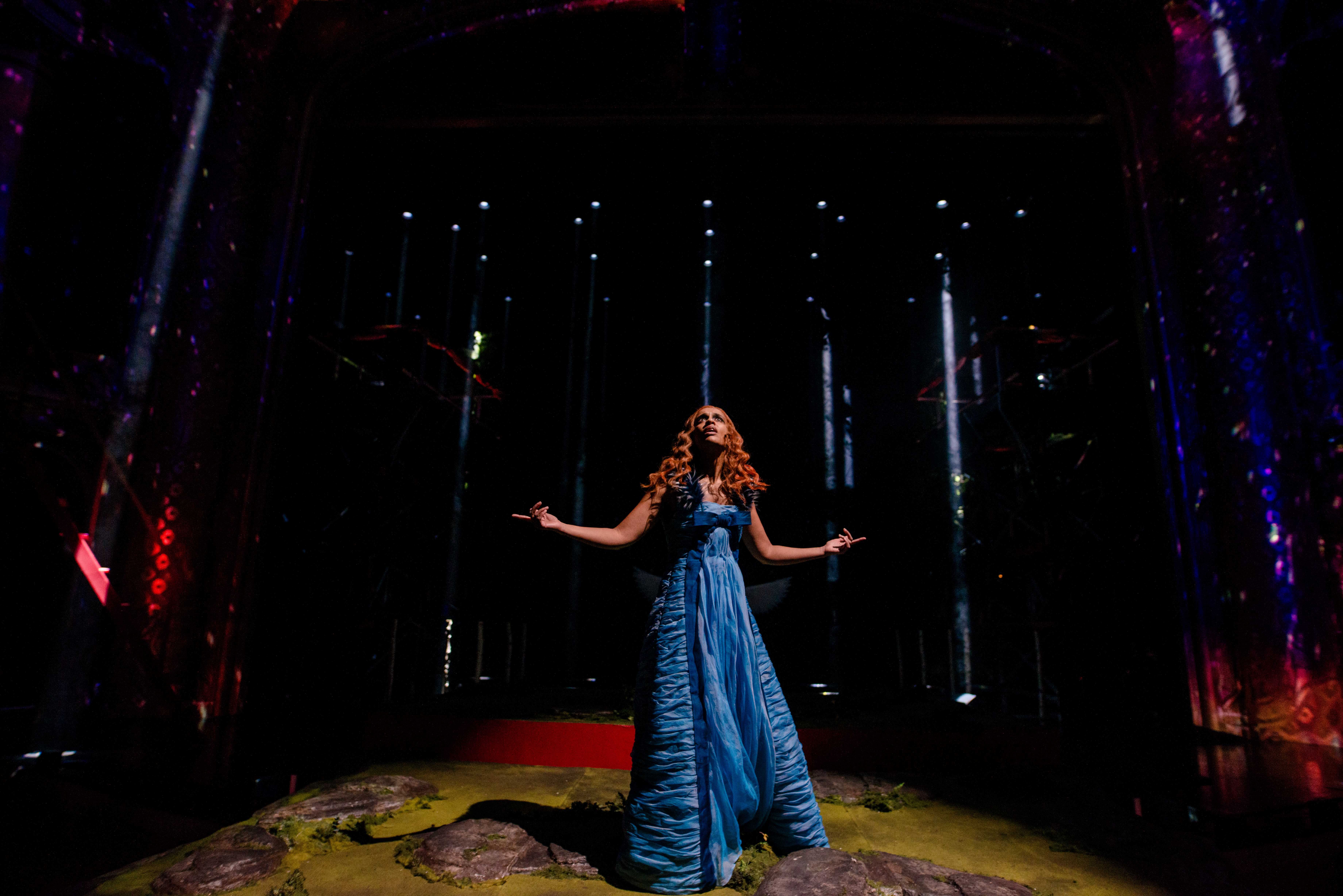 Kvinne i blå kjole på mørk scene