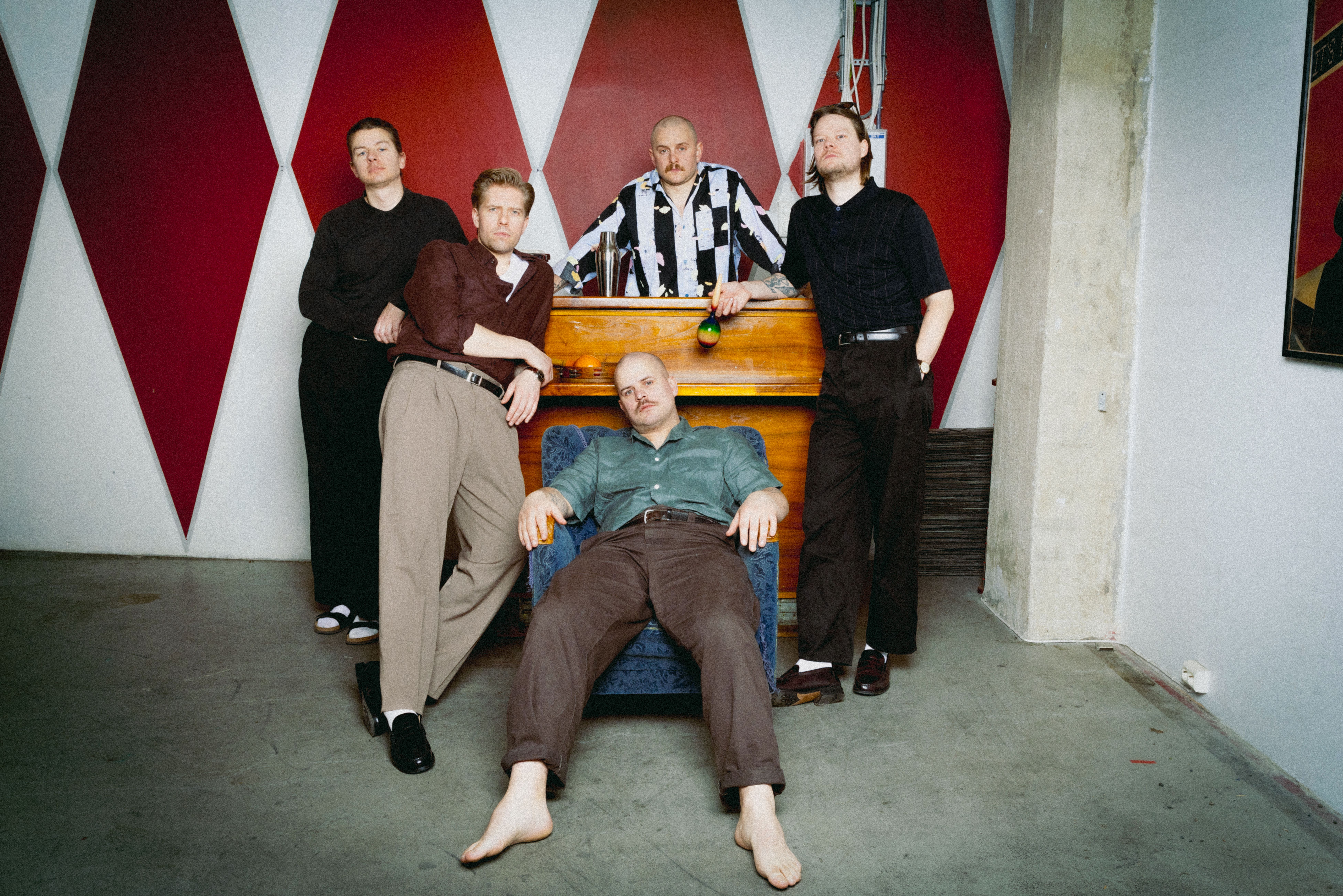 Fem unge menn står henslengt rundt et piano.